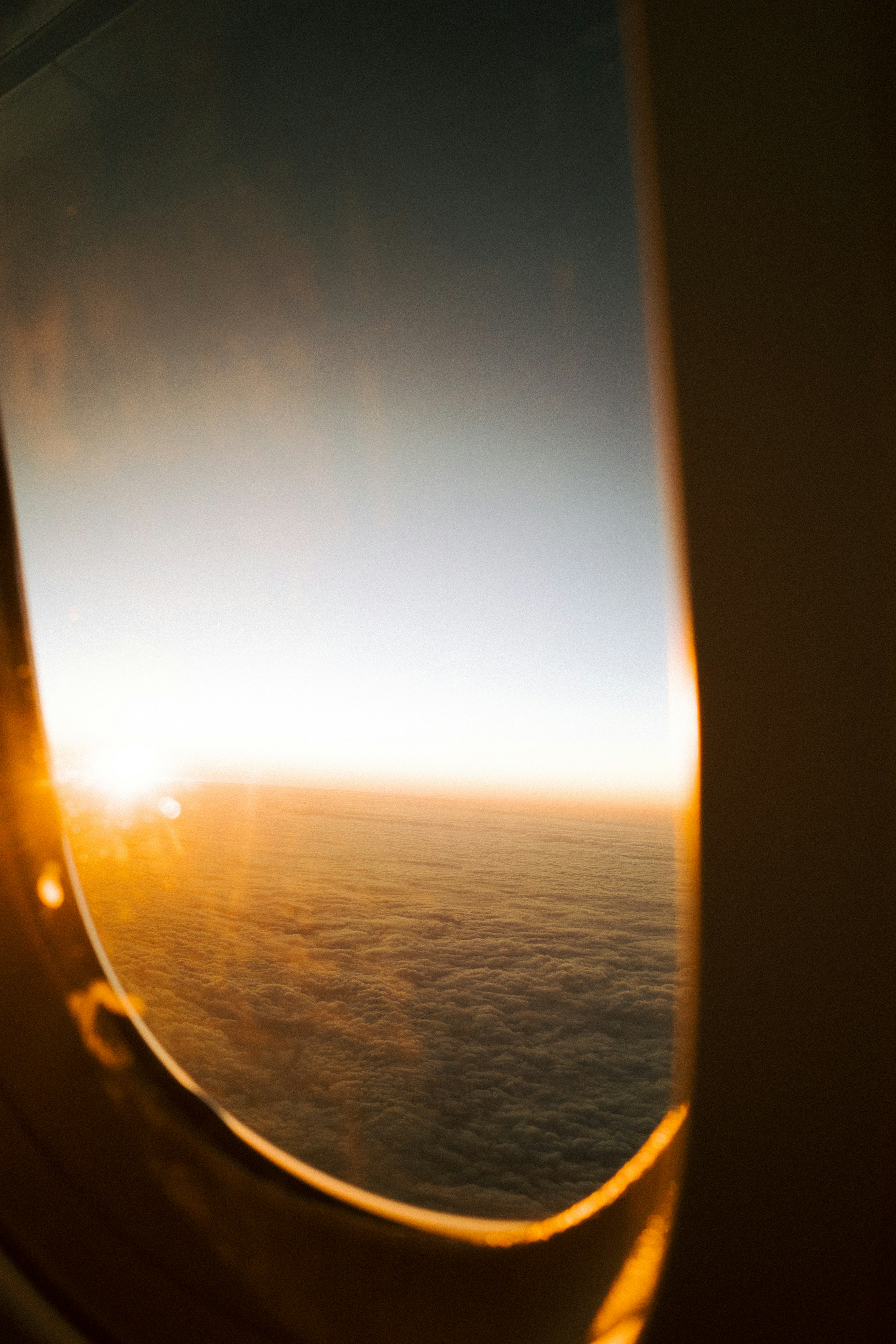 Sonnenuntergangsblick aus einem Flugzeugfenster über den Wolken