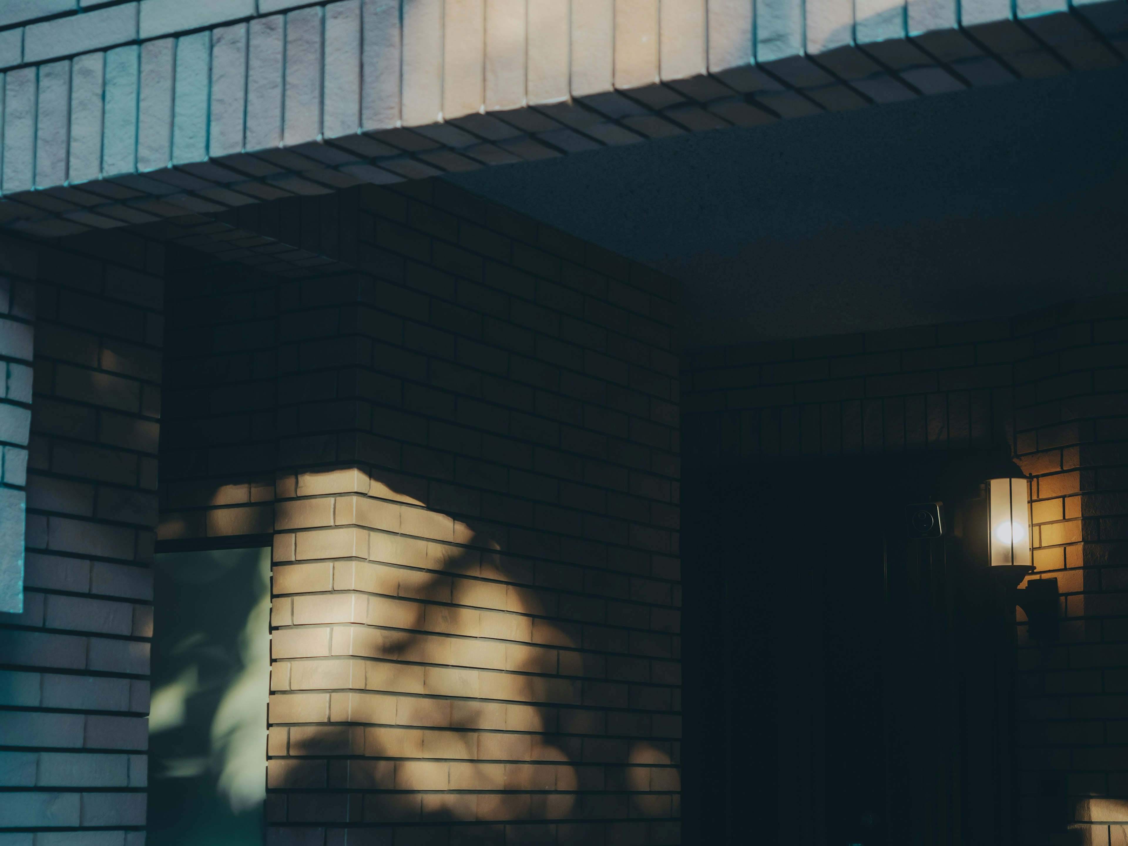 Gebäudeeingang mit Schatten an der Wand und einer Leuchte