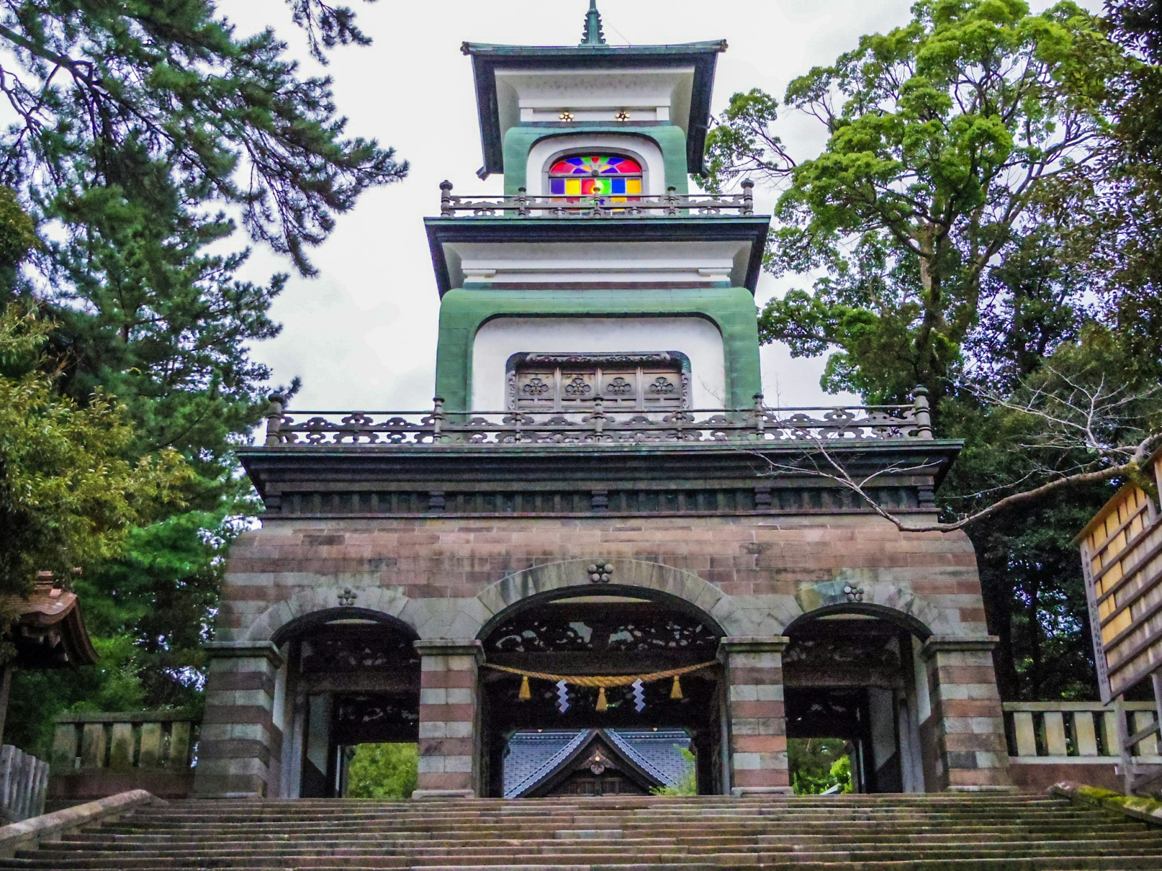 Front view of a historical building with a green roof and colorful stained glass