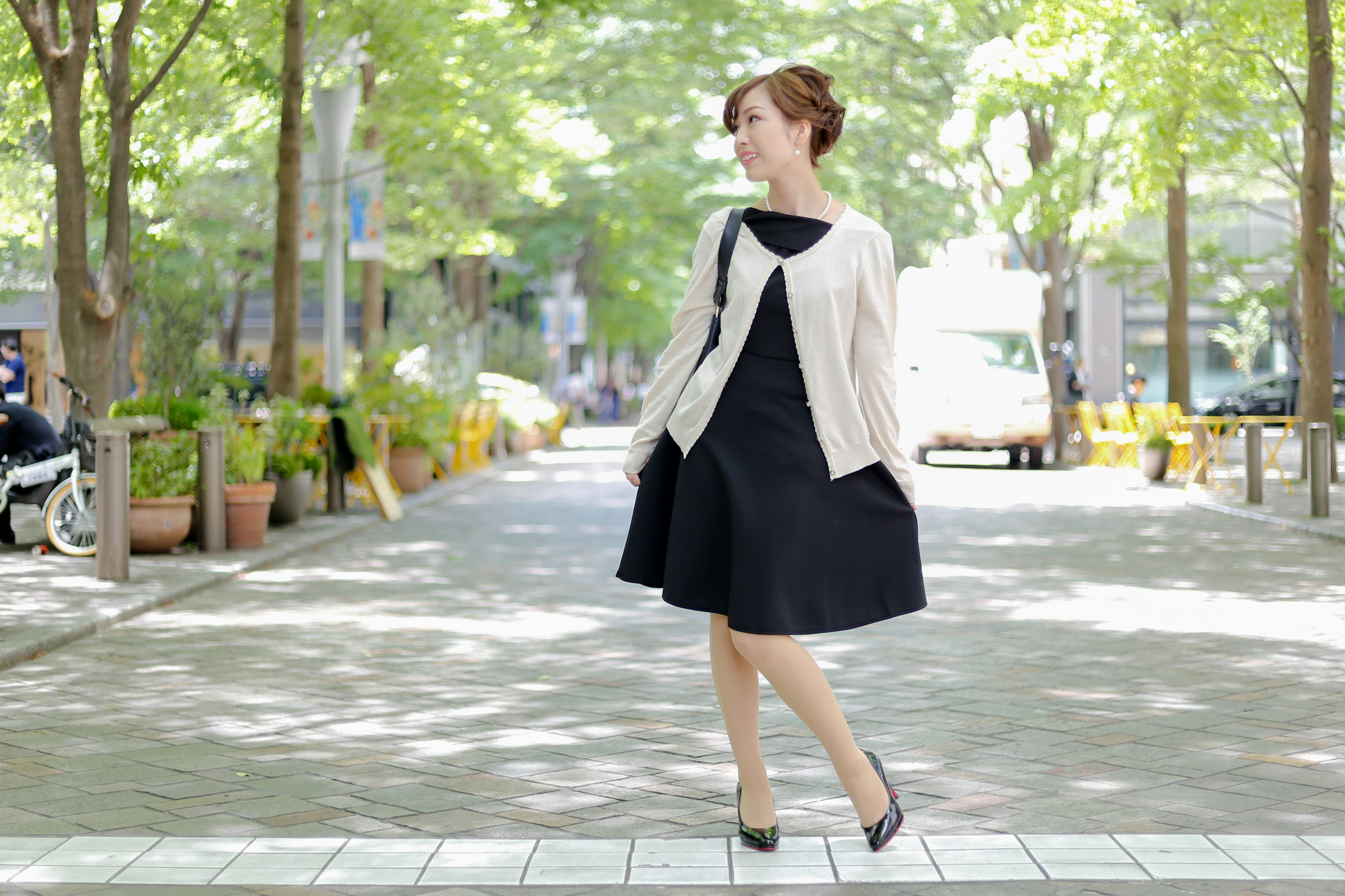 A woman in a black dress standing in a park