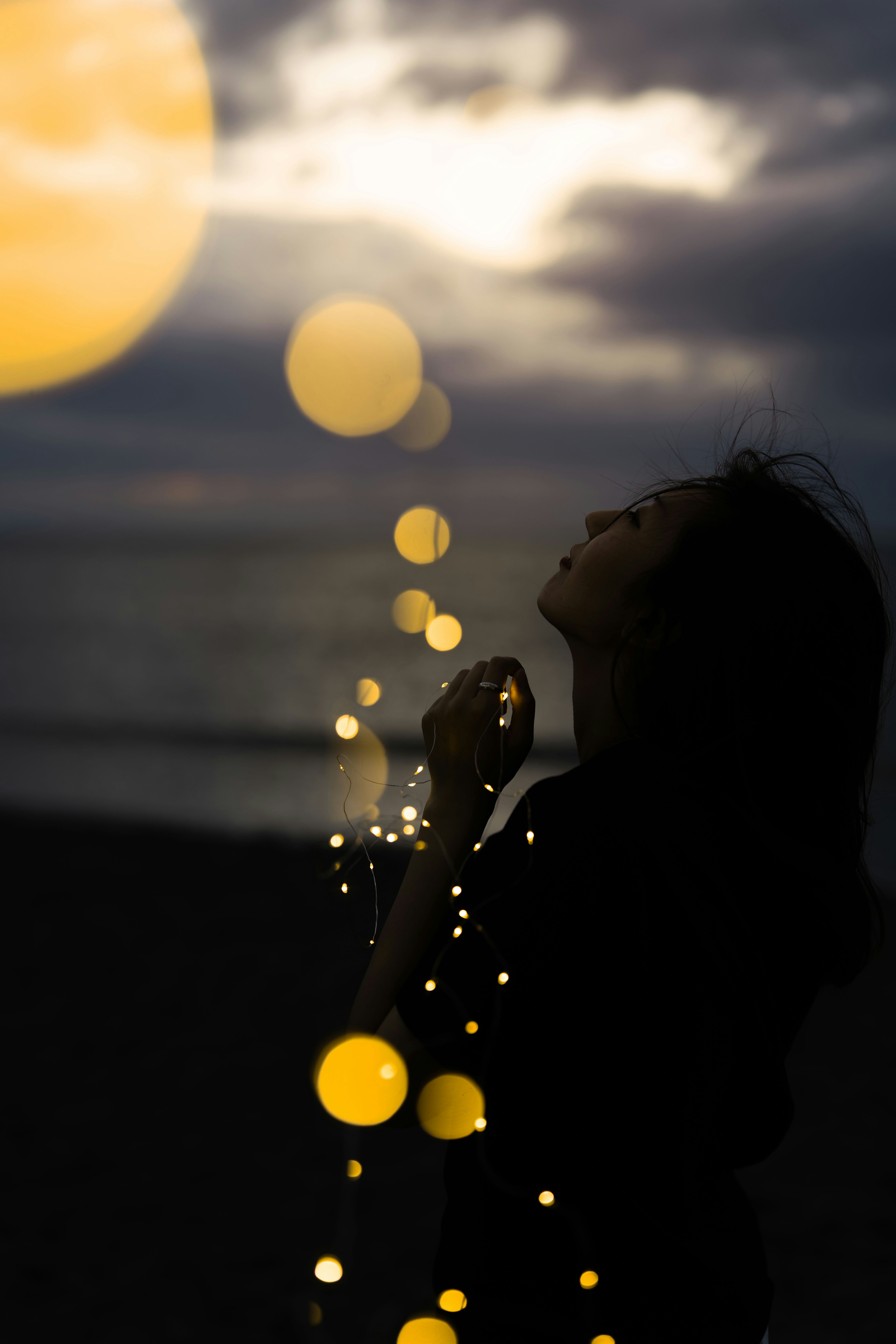 Woman praying at the beach with ethereal light effects