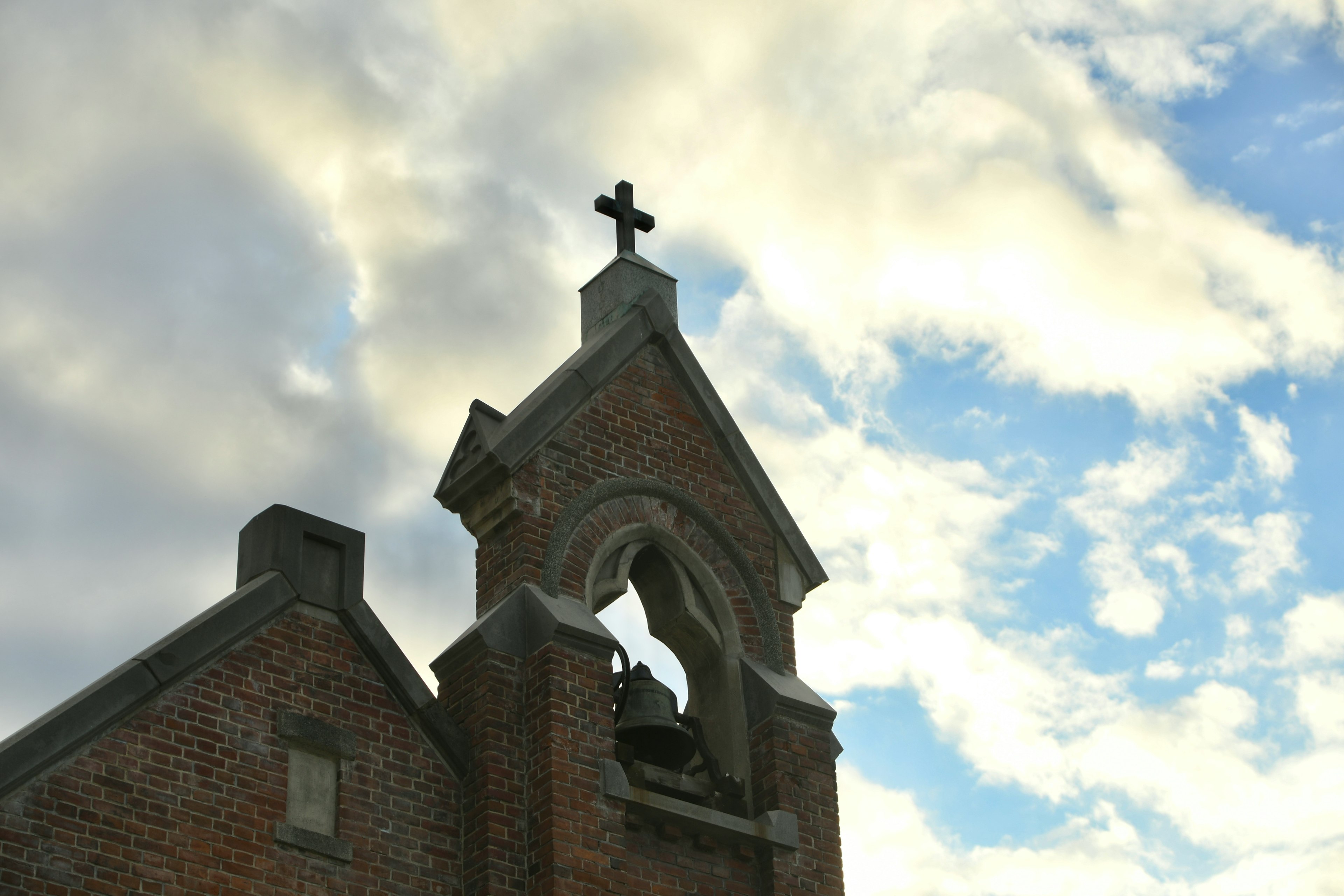 Campanario de iglesia con una cruz contra un cielo nublado