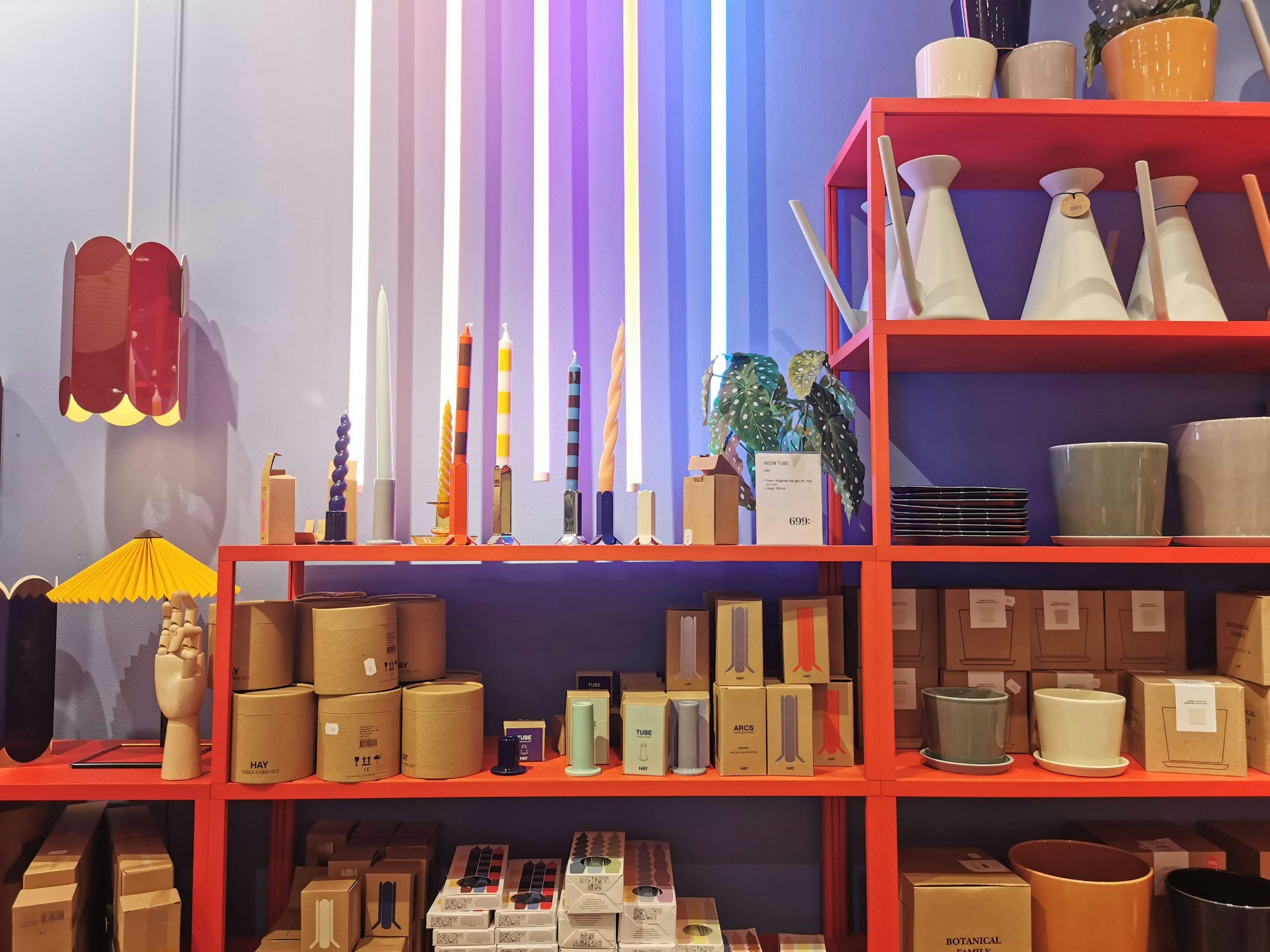 Colorful interior decor items displayed on a red shelf with vibrant lights above