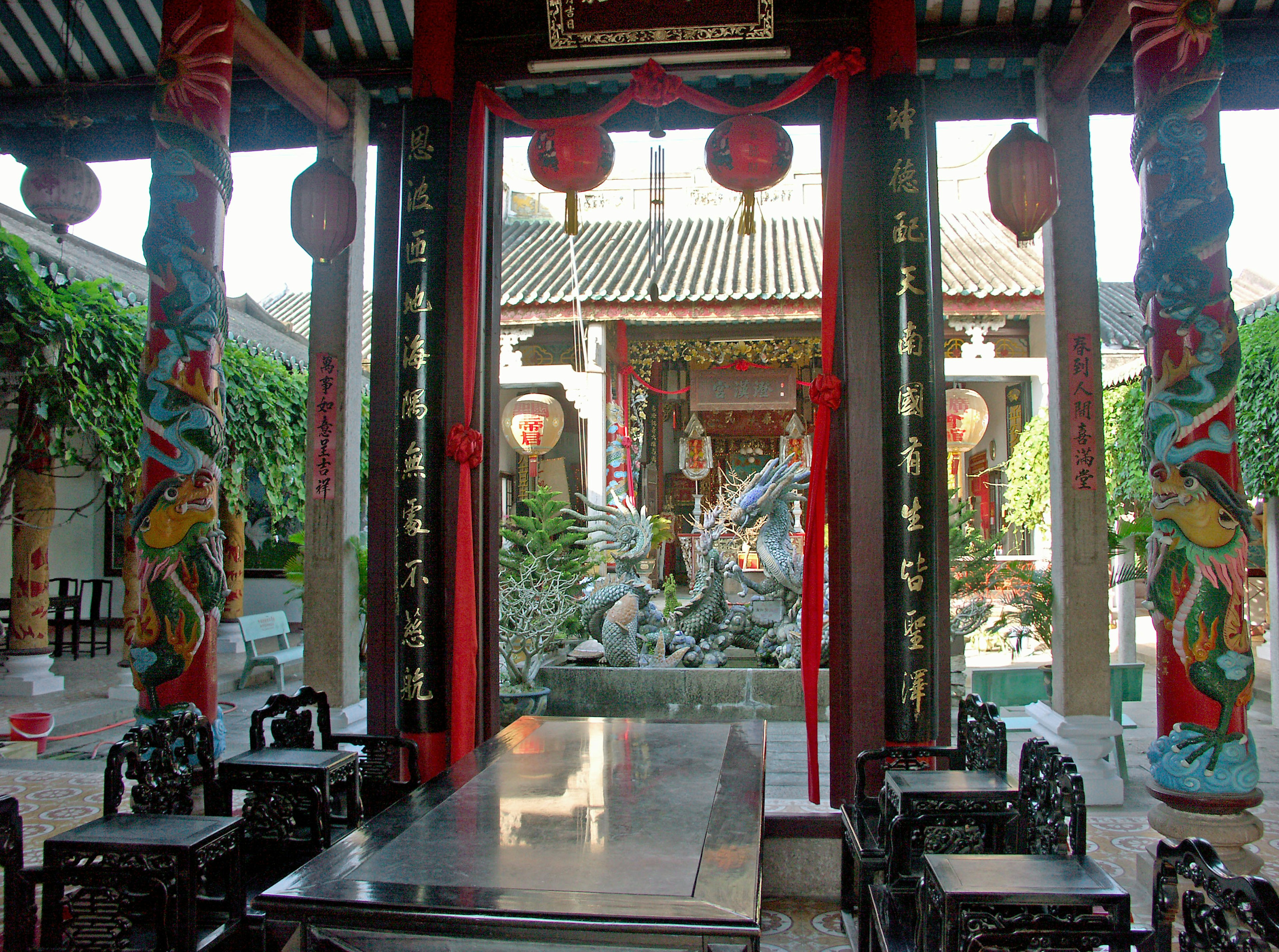 Vista interior de un jardín chino tradicional con pilares ornamentados y una escultura de piedra