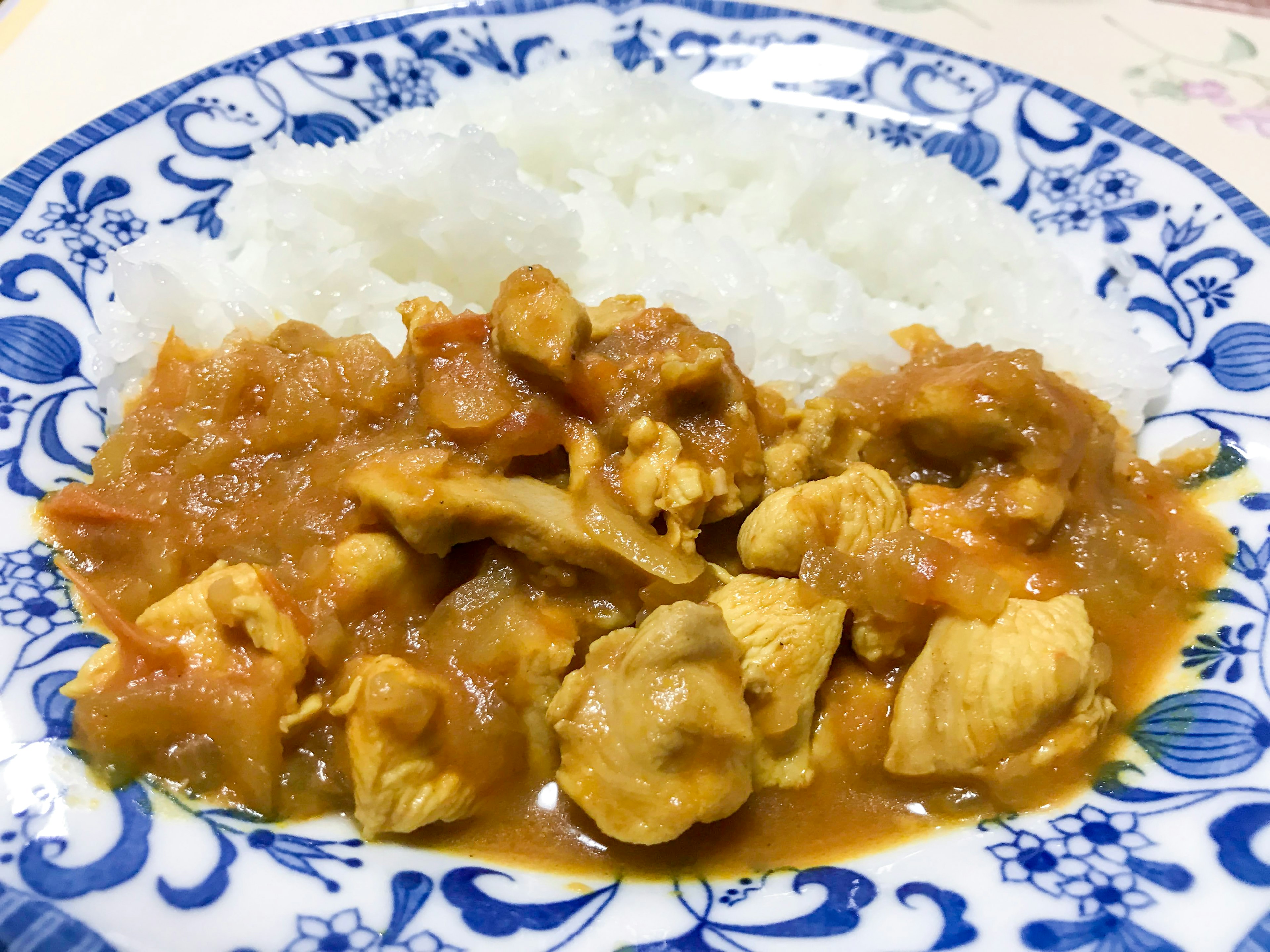 Imagen de un plato con curry y arroz que presenta curry de pollo servido en un plato con un patrón floral azul