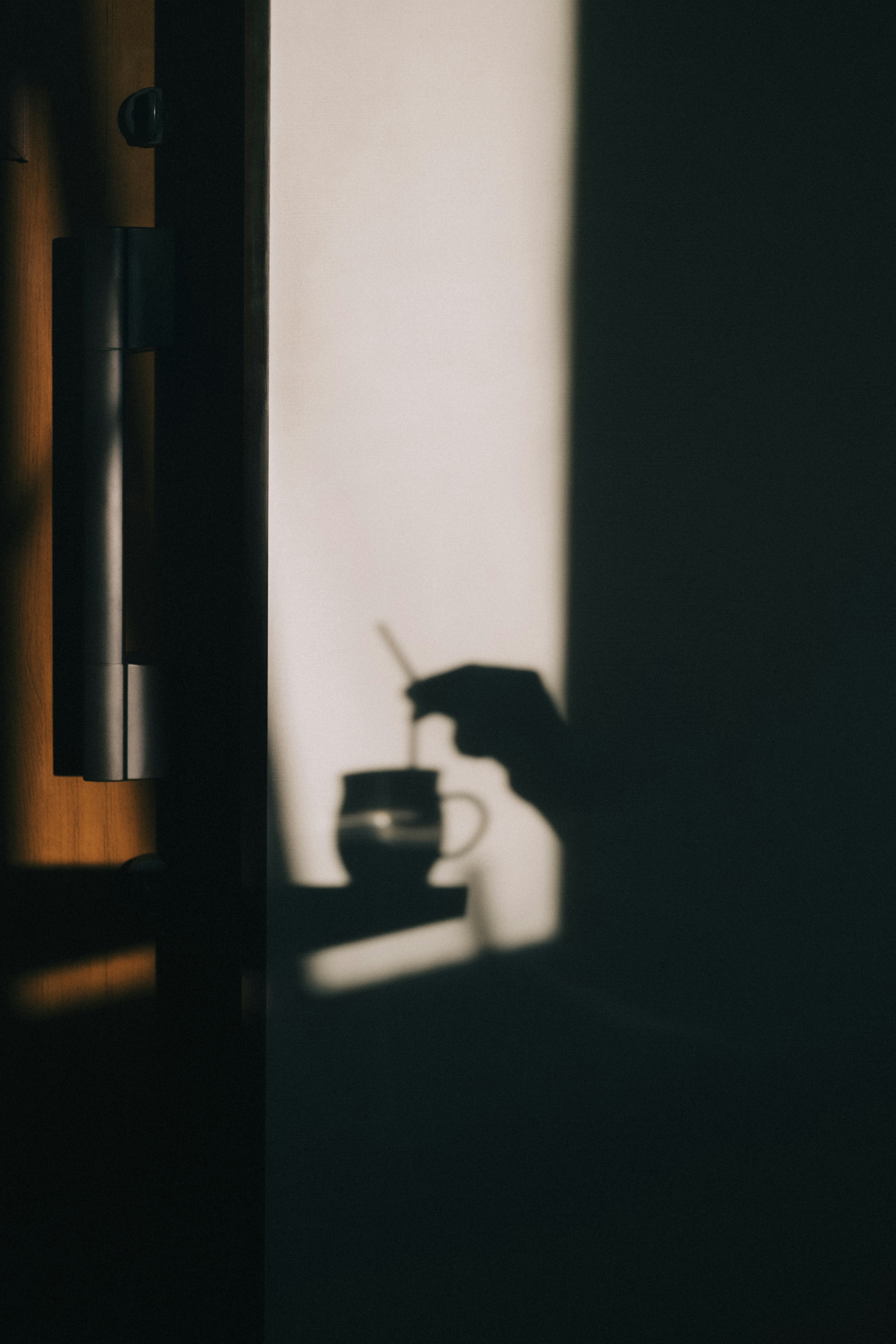 Sombra de una mano sosteniendo una cuchara sobre una taza de café