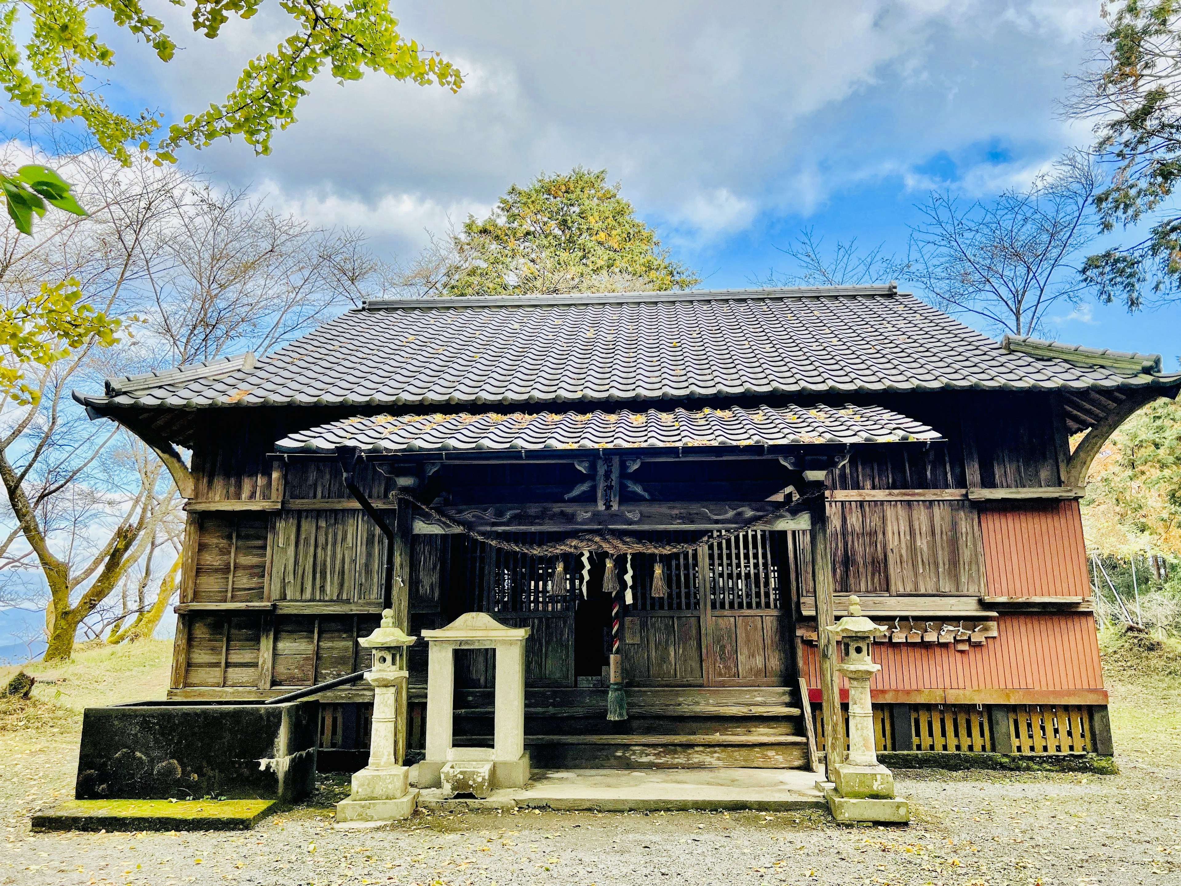 Traditional Japanese building wooden shrine with green trees and sky in the background