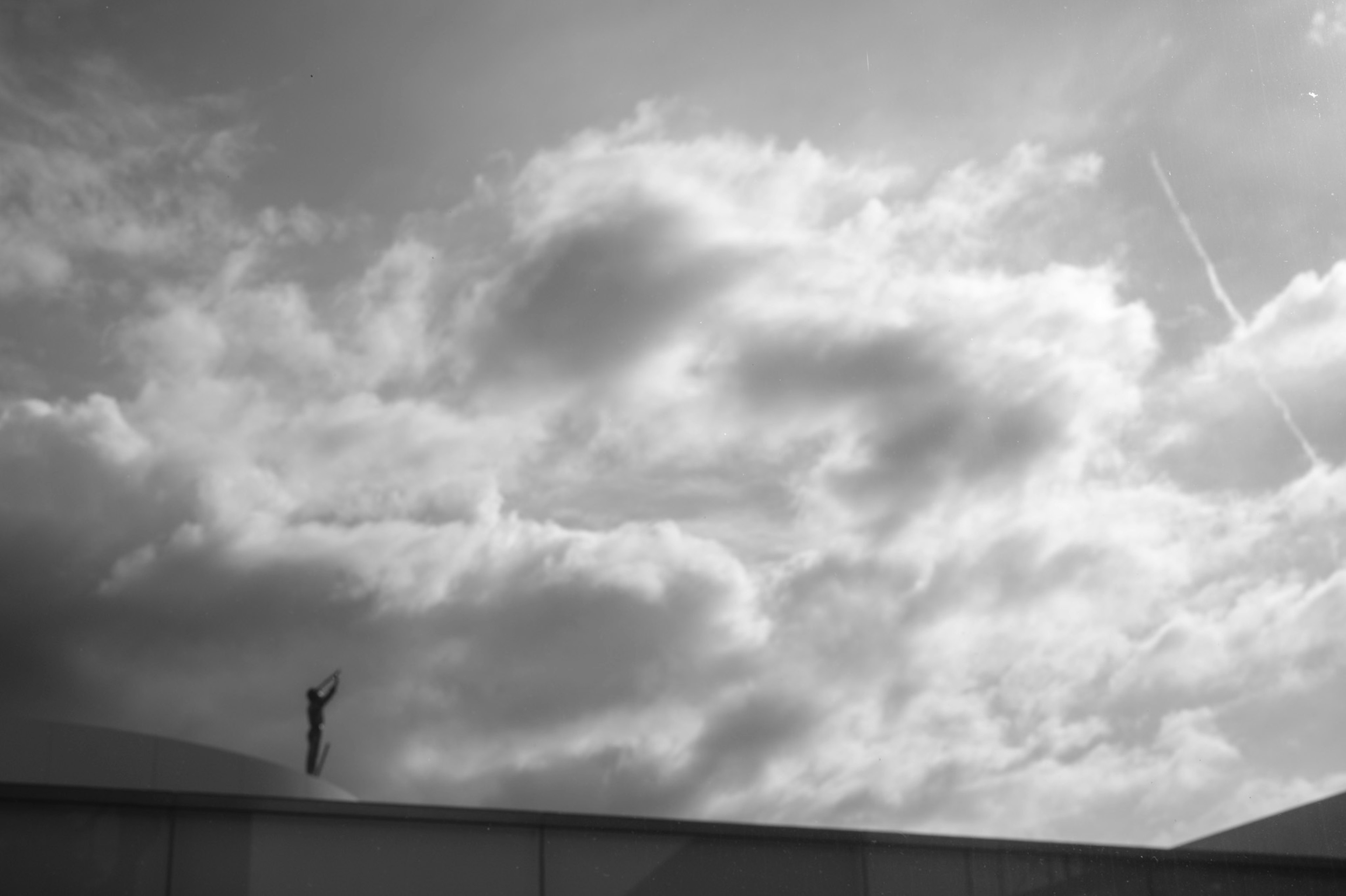 雲が広がる空の上に立つ人影のシルエット