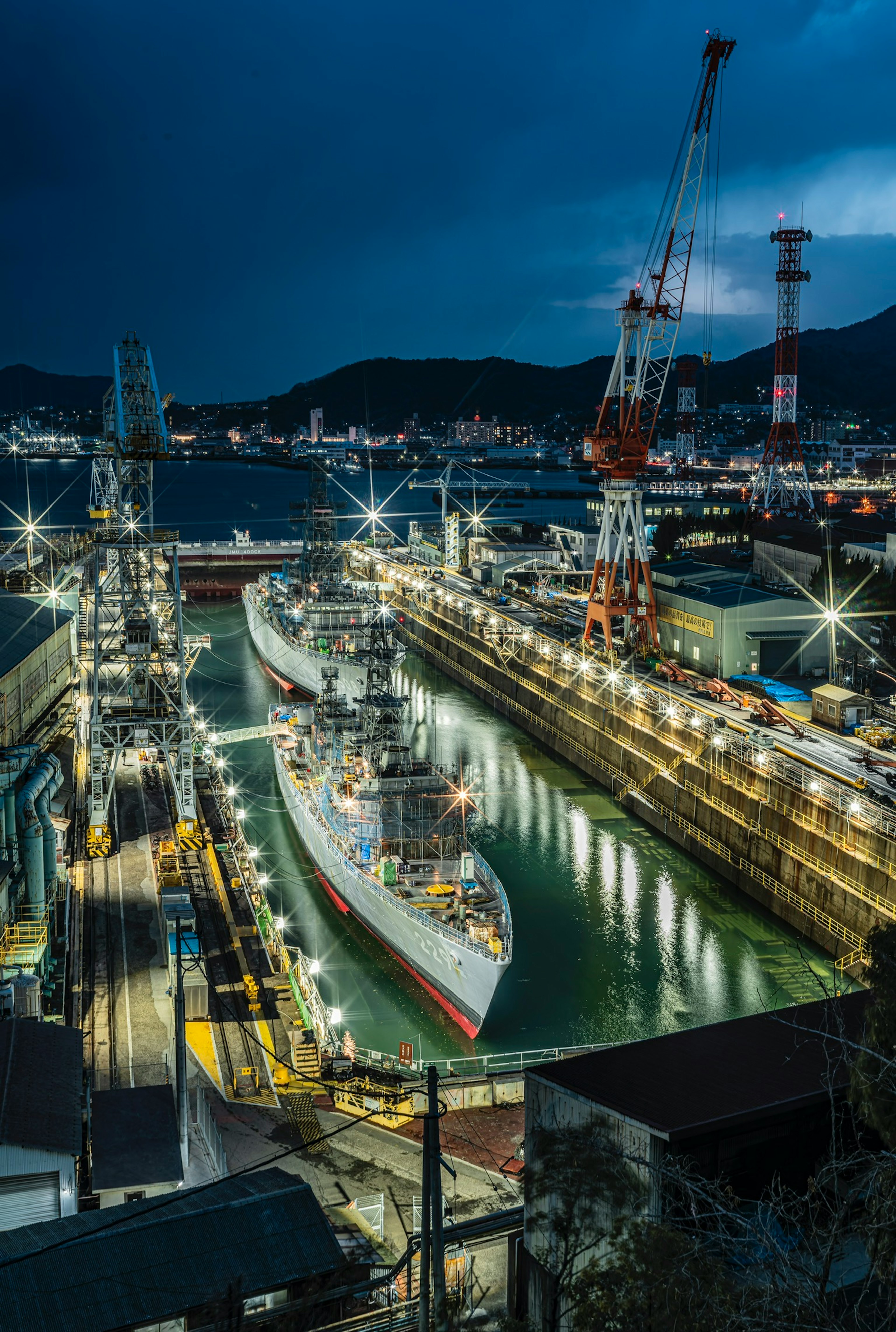 Vista nocturna de un puerto con barcos amarrados y grúas iluminadas