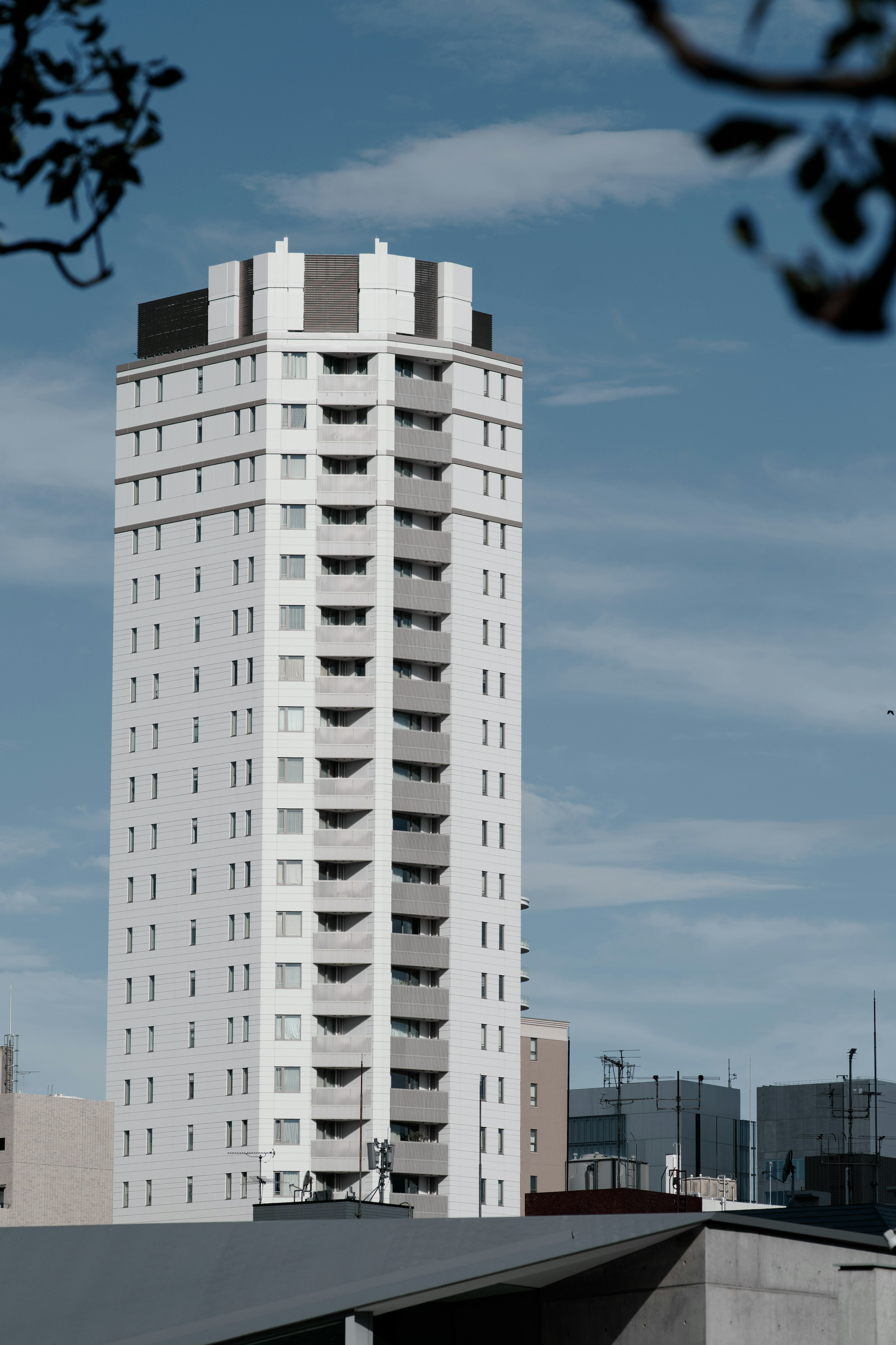 Bangunan apartemen putih tinggi dengan balkon di bawah langit biru