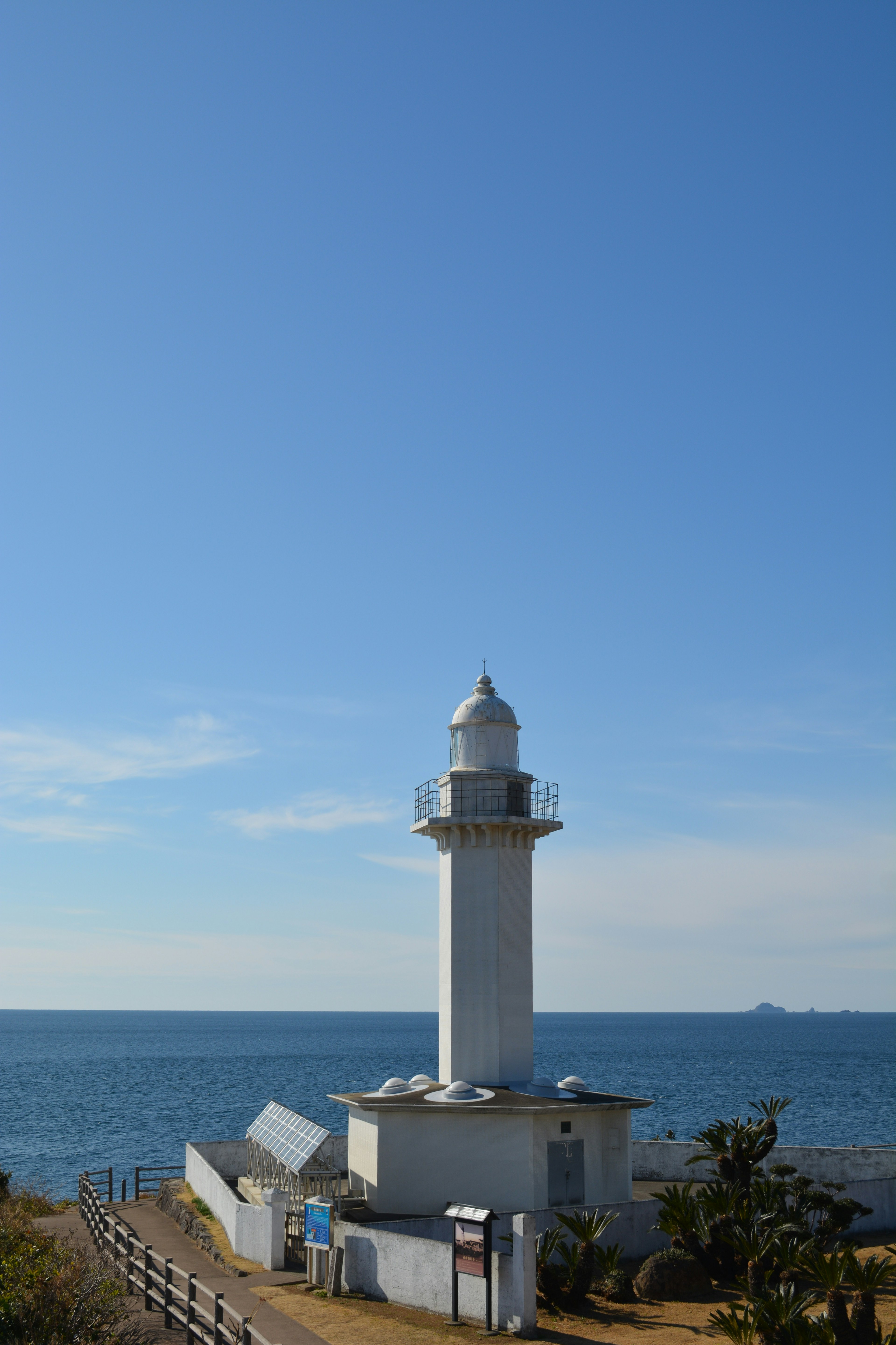 Faro blanco de pie contra un mar y un cielo azules