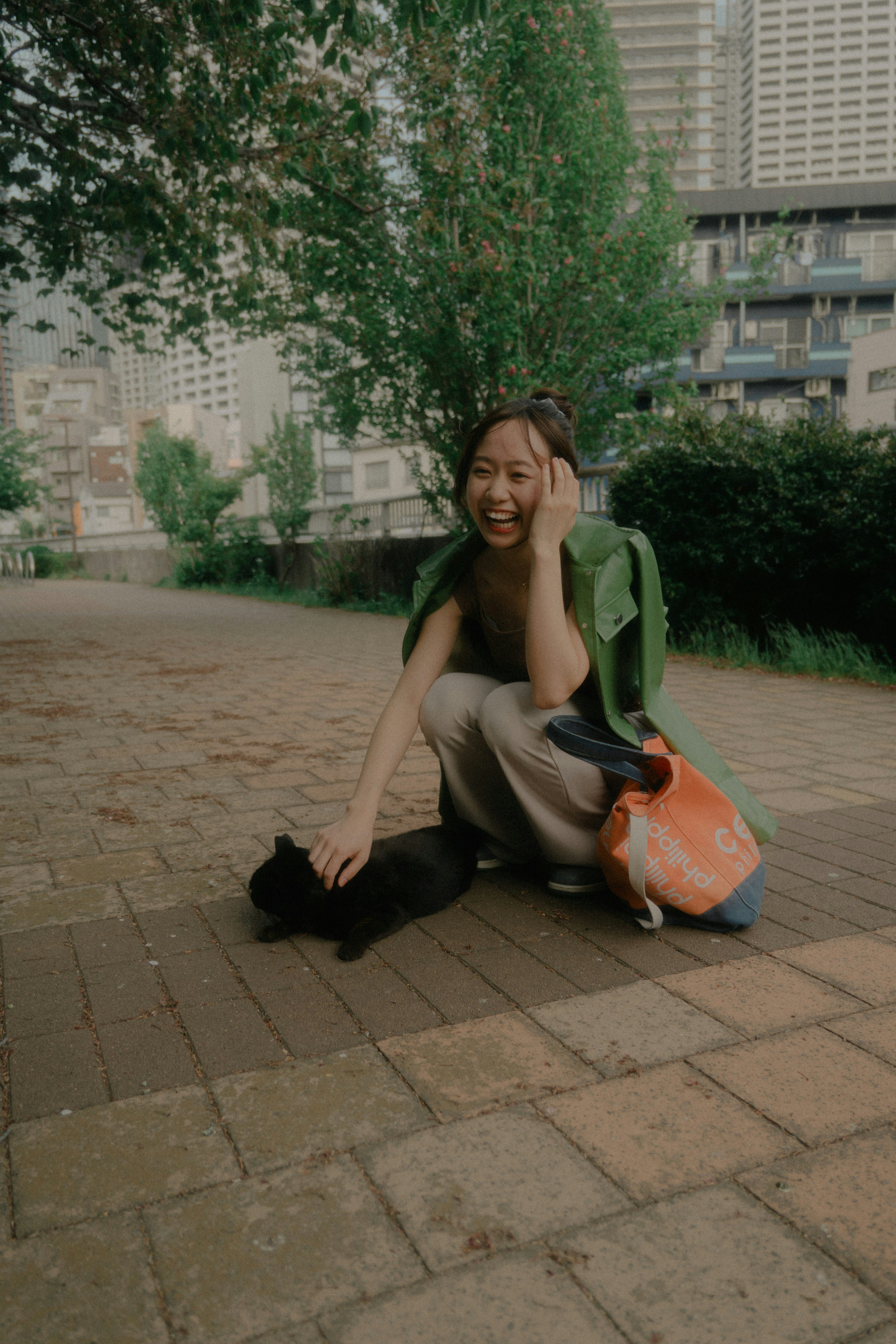 公園で黒い猫と遊んでいる女性の笑顔の写真