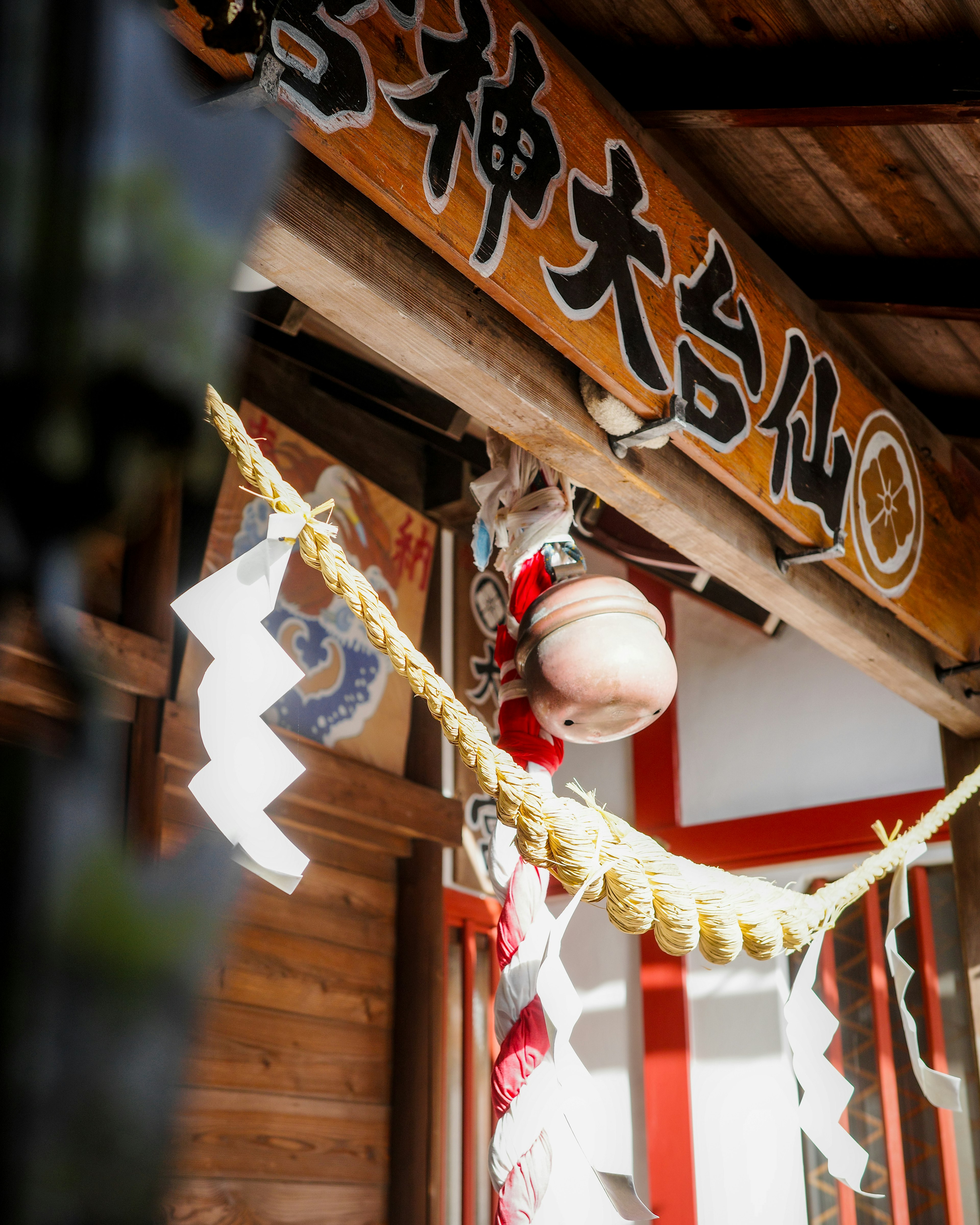 Decorative entrance of a traditional shrine with a bell and sacred rope