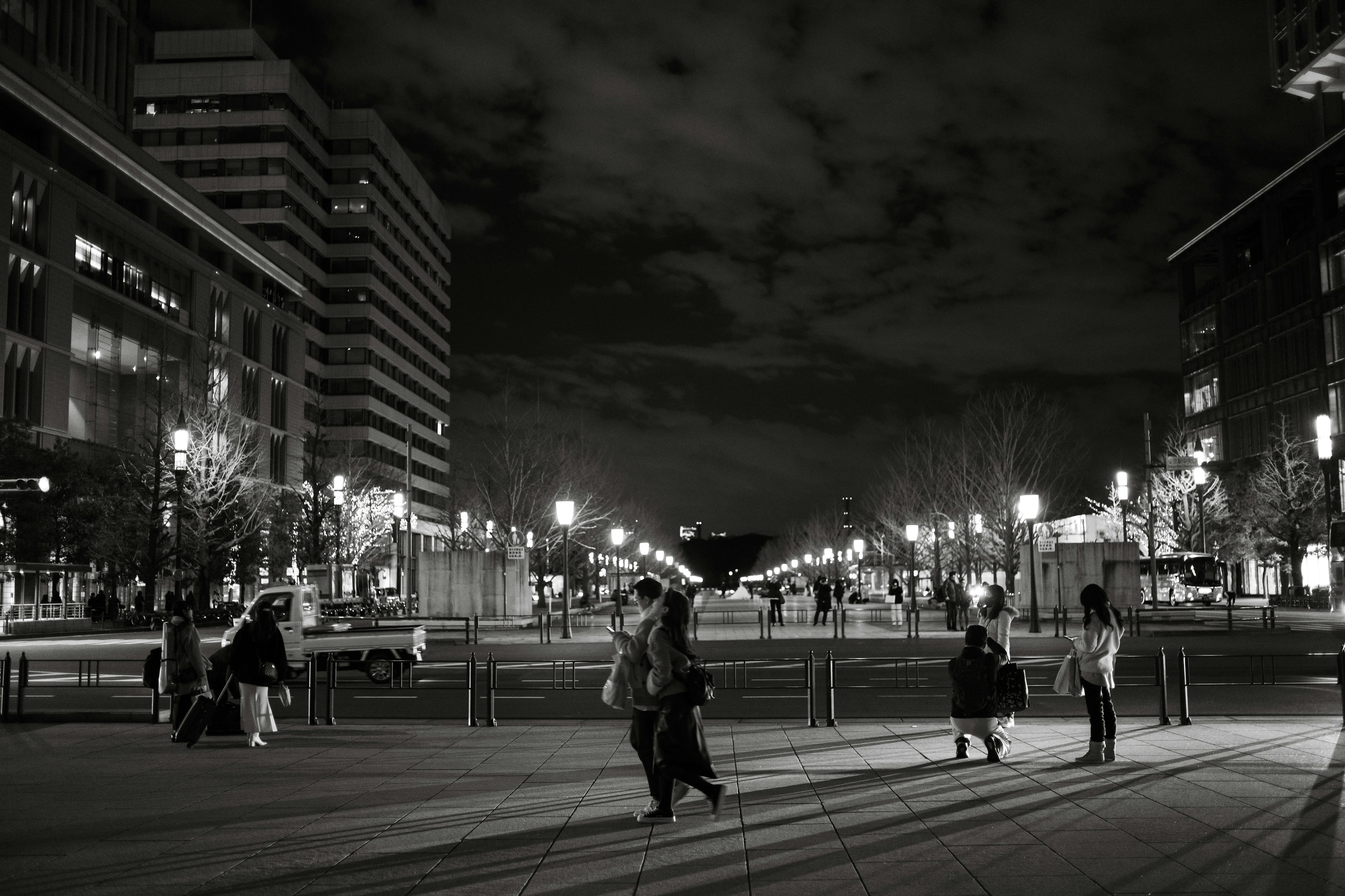 Persone che camminano in una strada di città di notte con silhouette di edifici