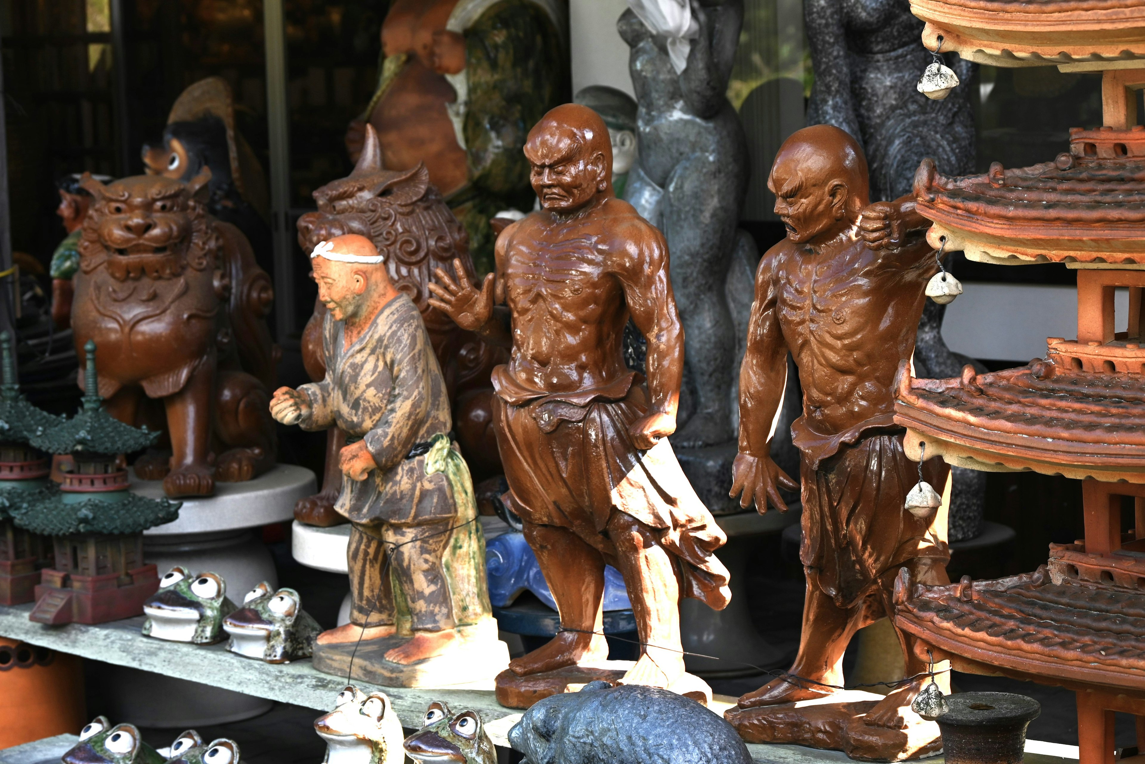 Sculptures en bois exposées devant un magasin avec diverses figures