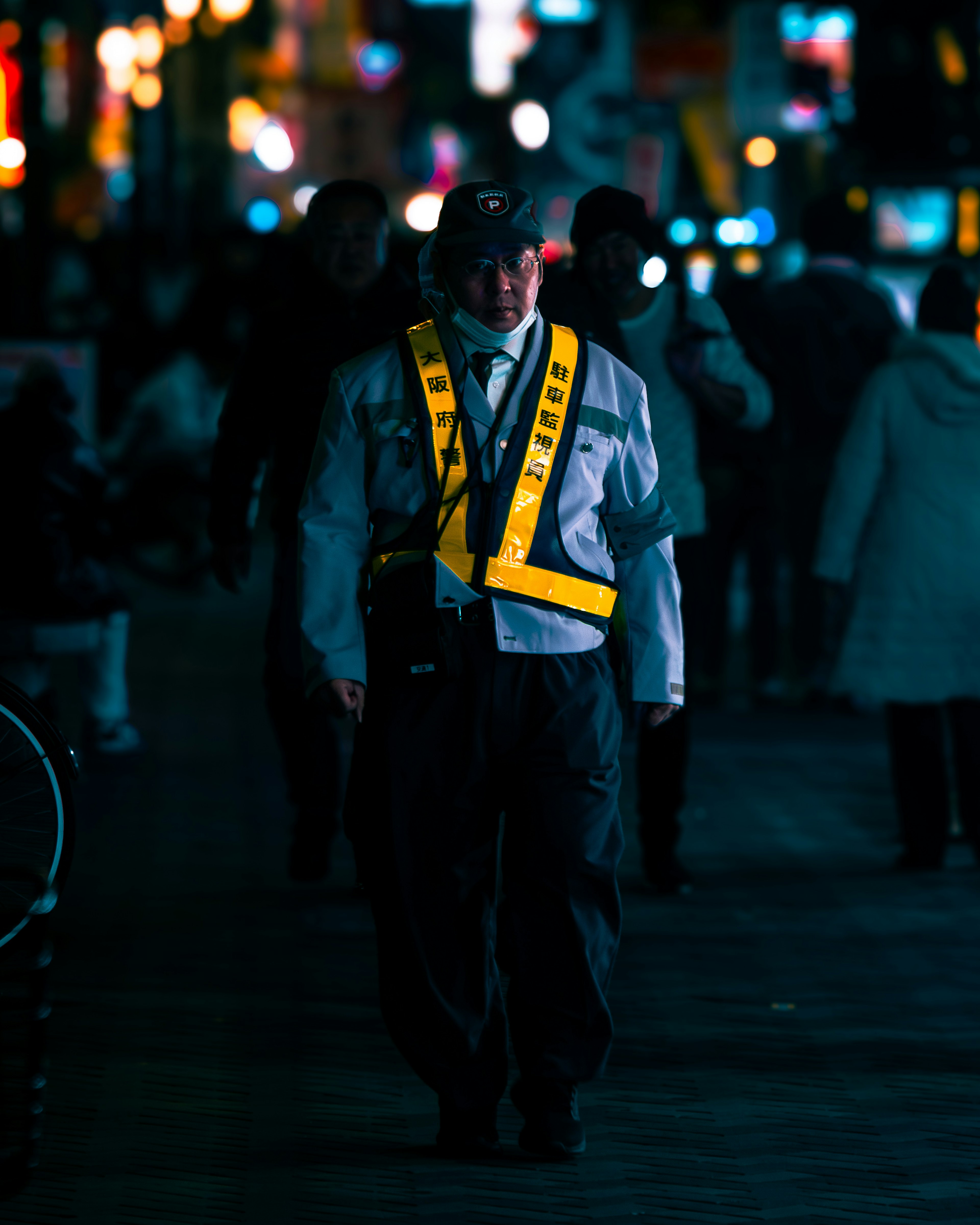 A security guard walking on a dark street wearing a reflective vest