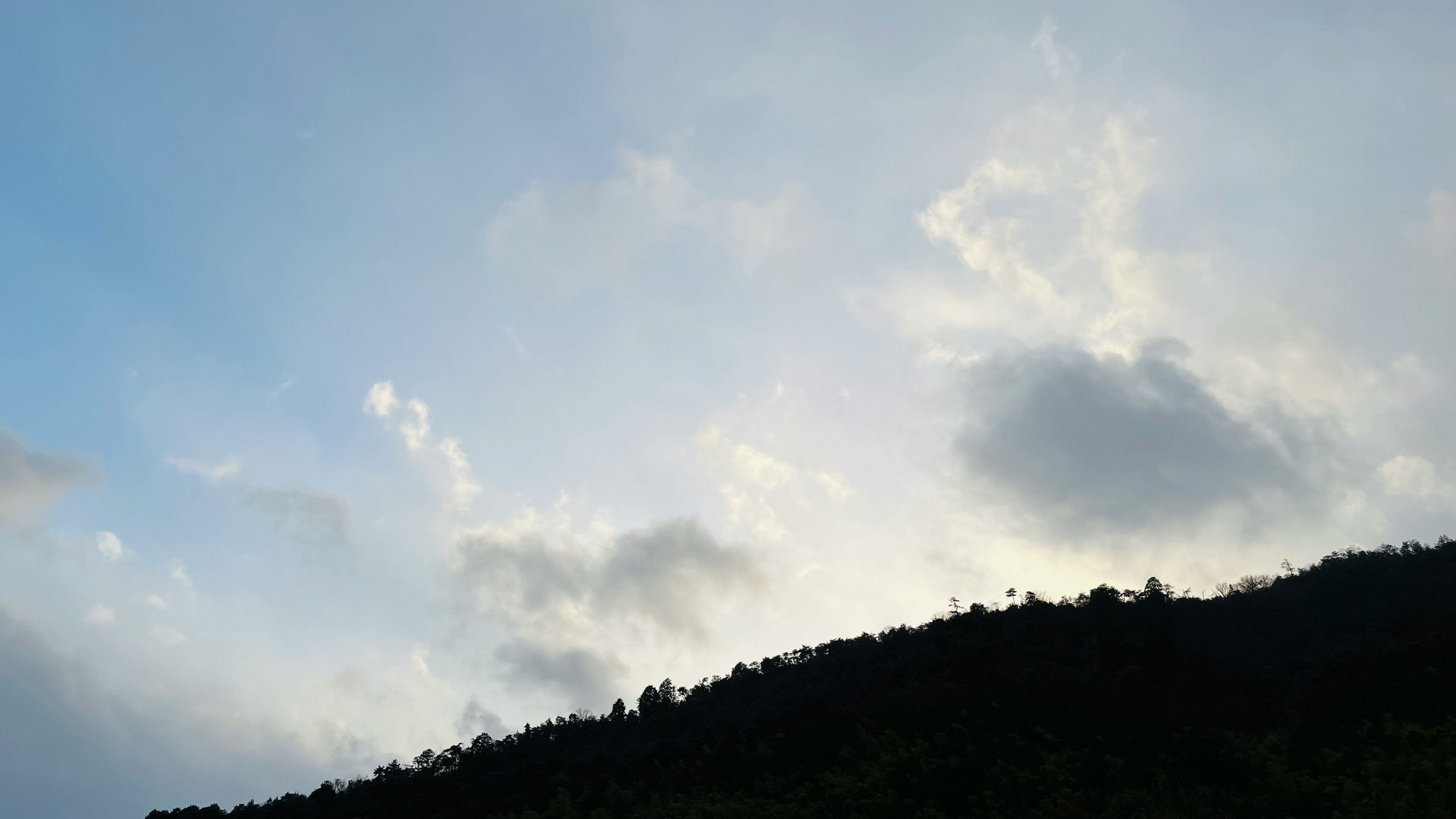 青空と雲に覆われた山のシルエット