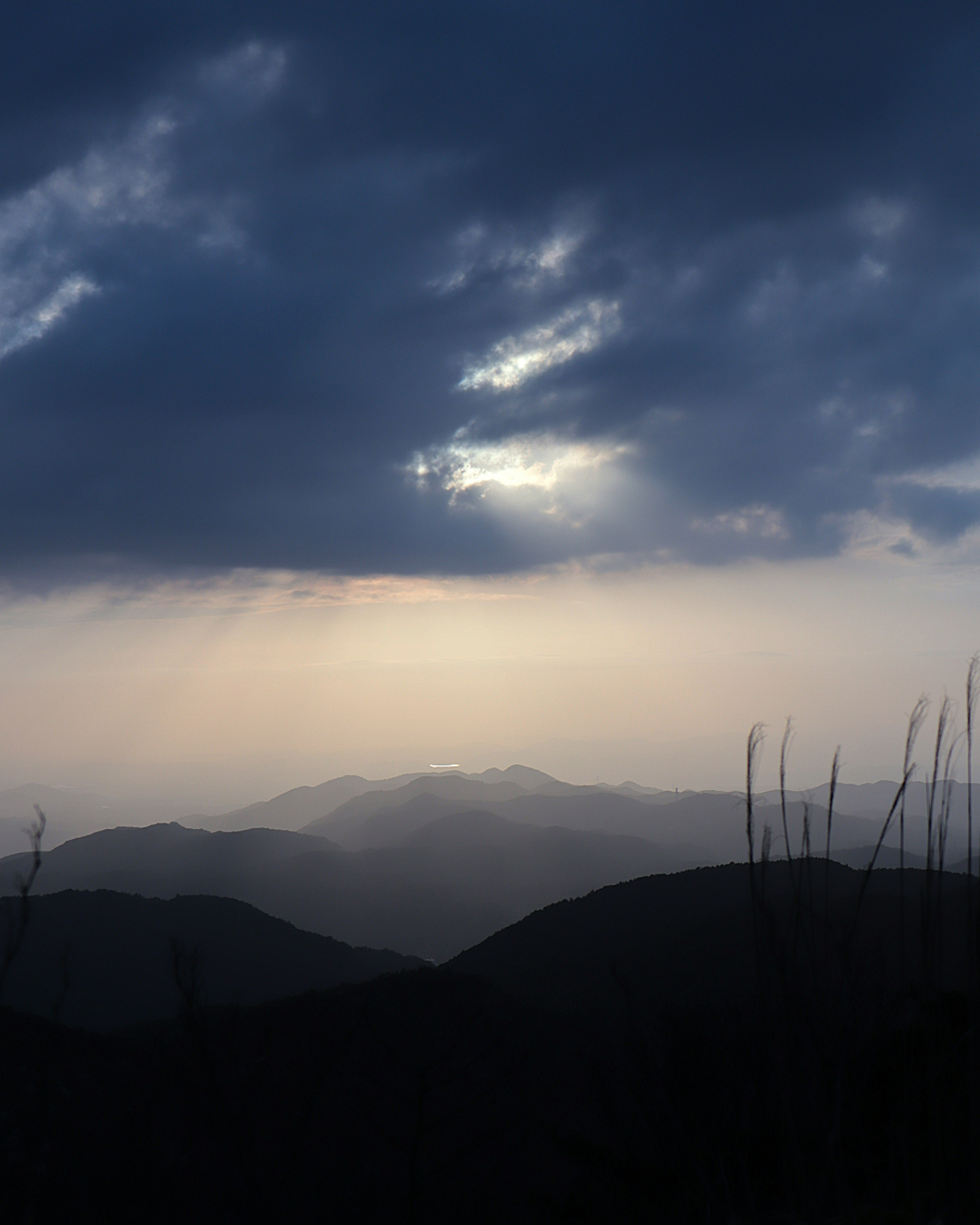 Un paisaje con nubes oscuras y montañas en silueta contra una luz suave