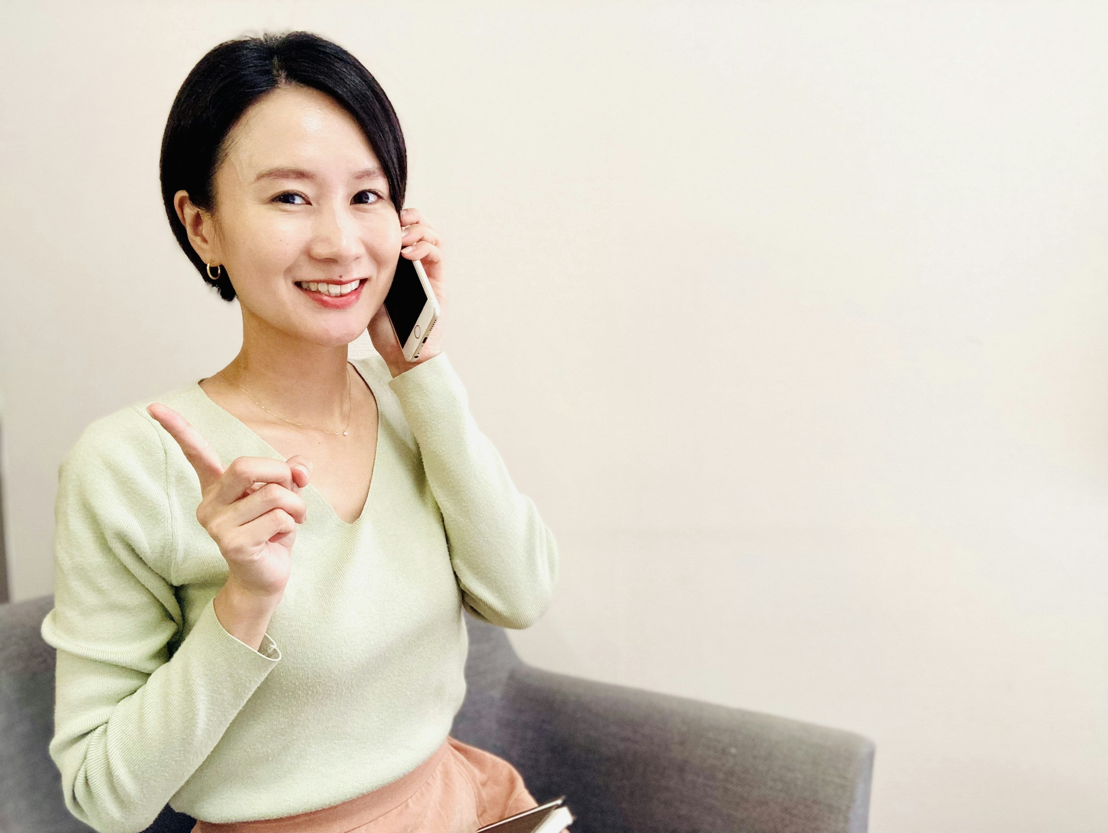 A smiling woman talking on the phone and pointing with her hand