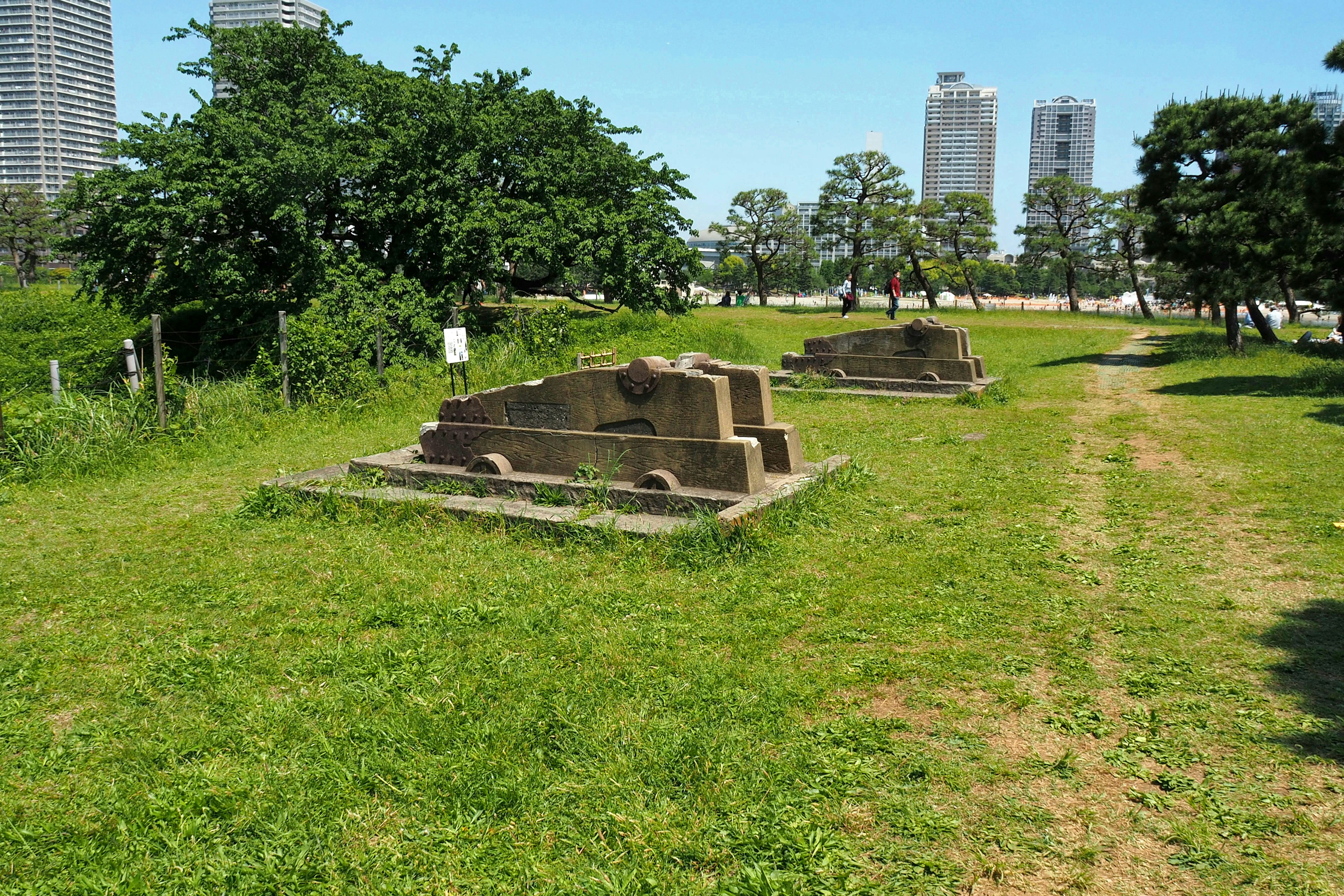 Ancient stone ruins on green grass with skyscrapers in the background