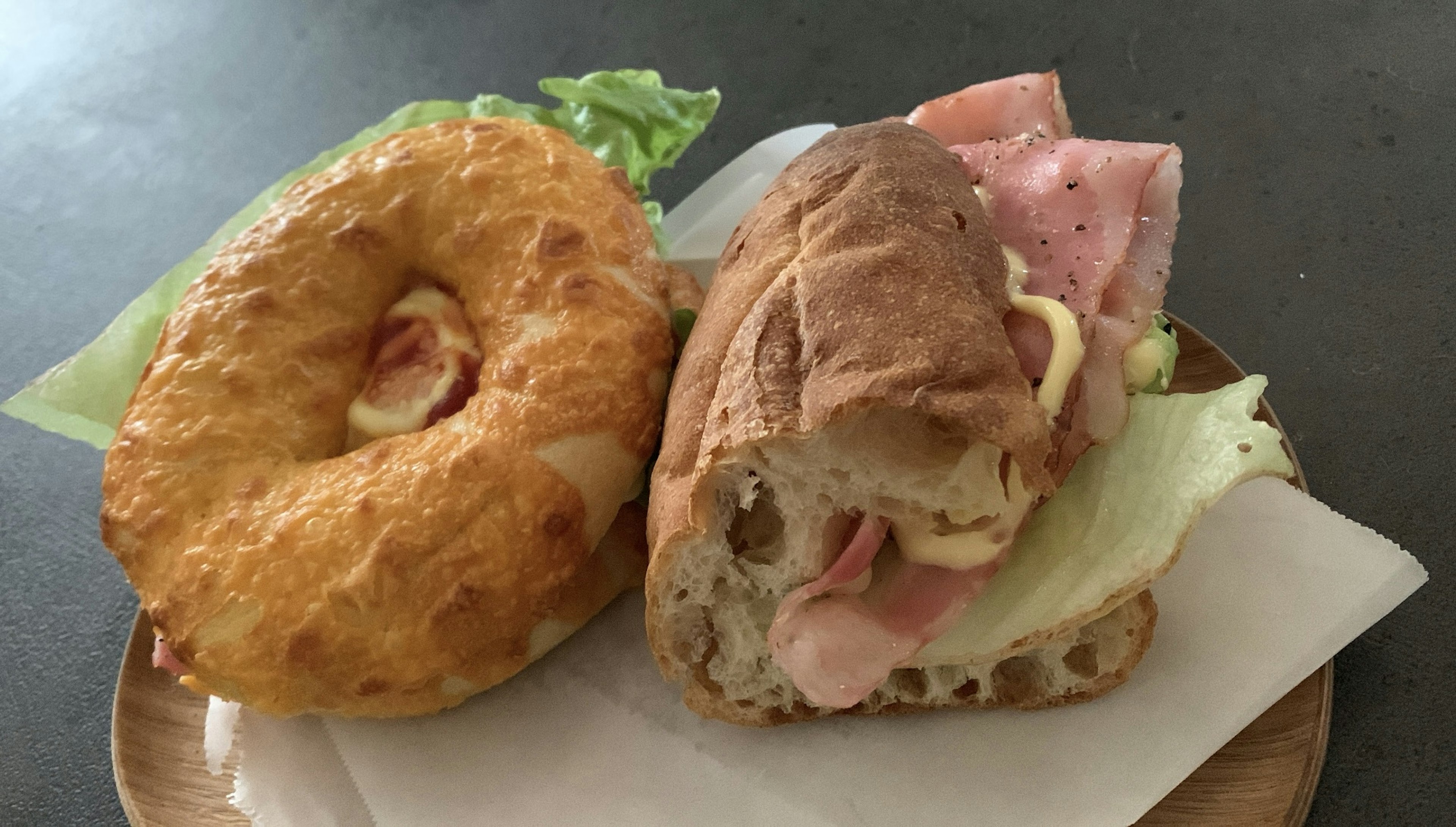 Bakery display featuring a sandwich and a bagel with lettuce and ham