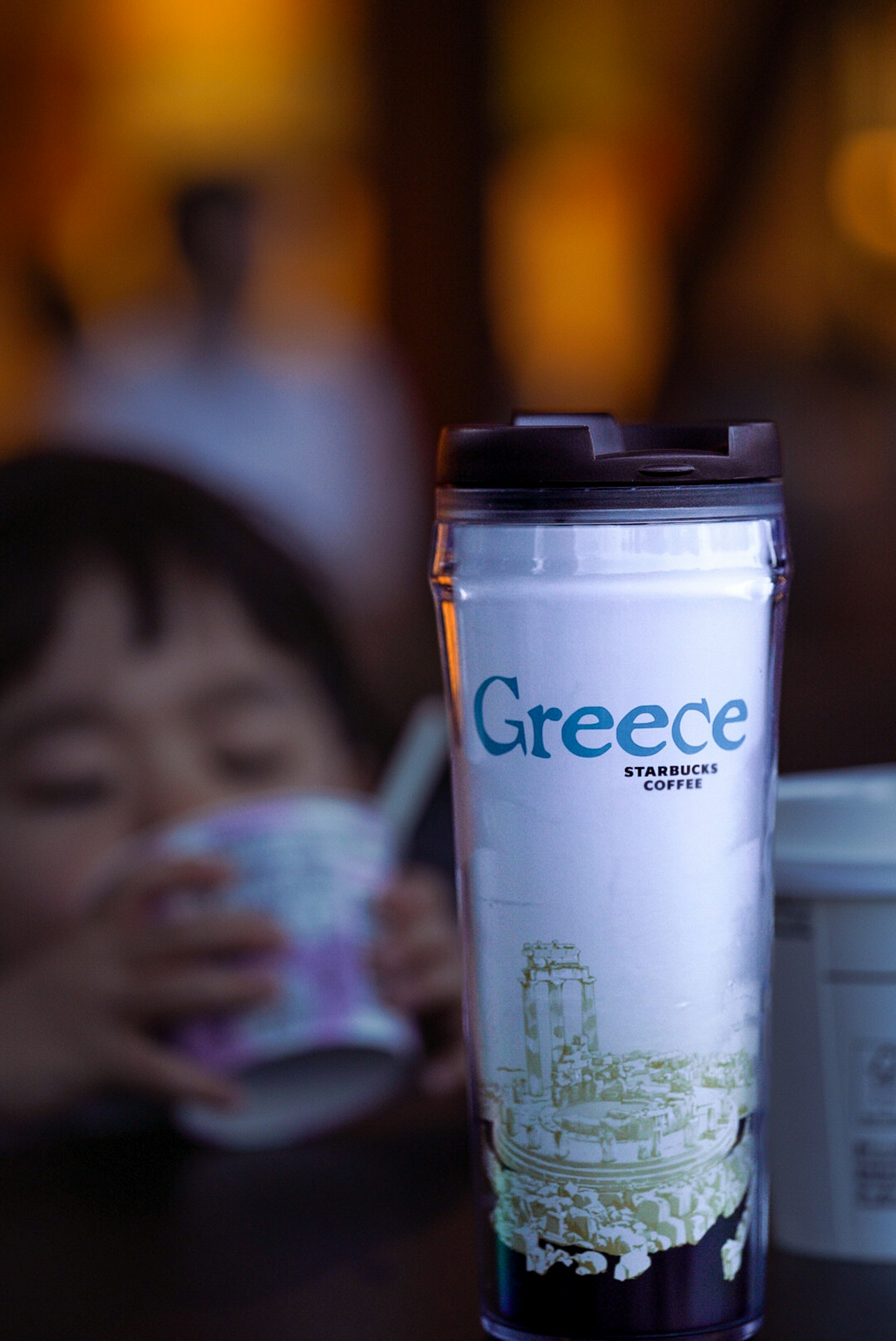 Enfant tenant une tasse avec un mug de voyage sur la Grèce au premier plan