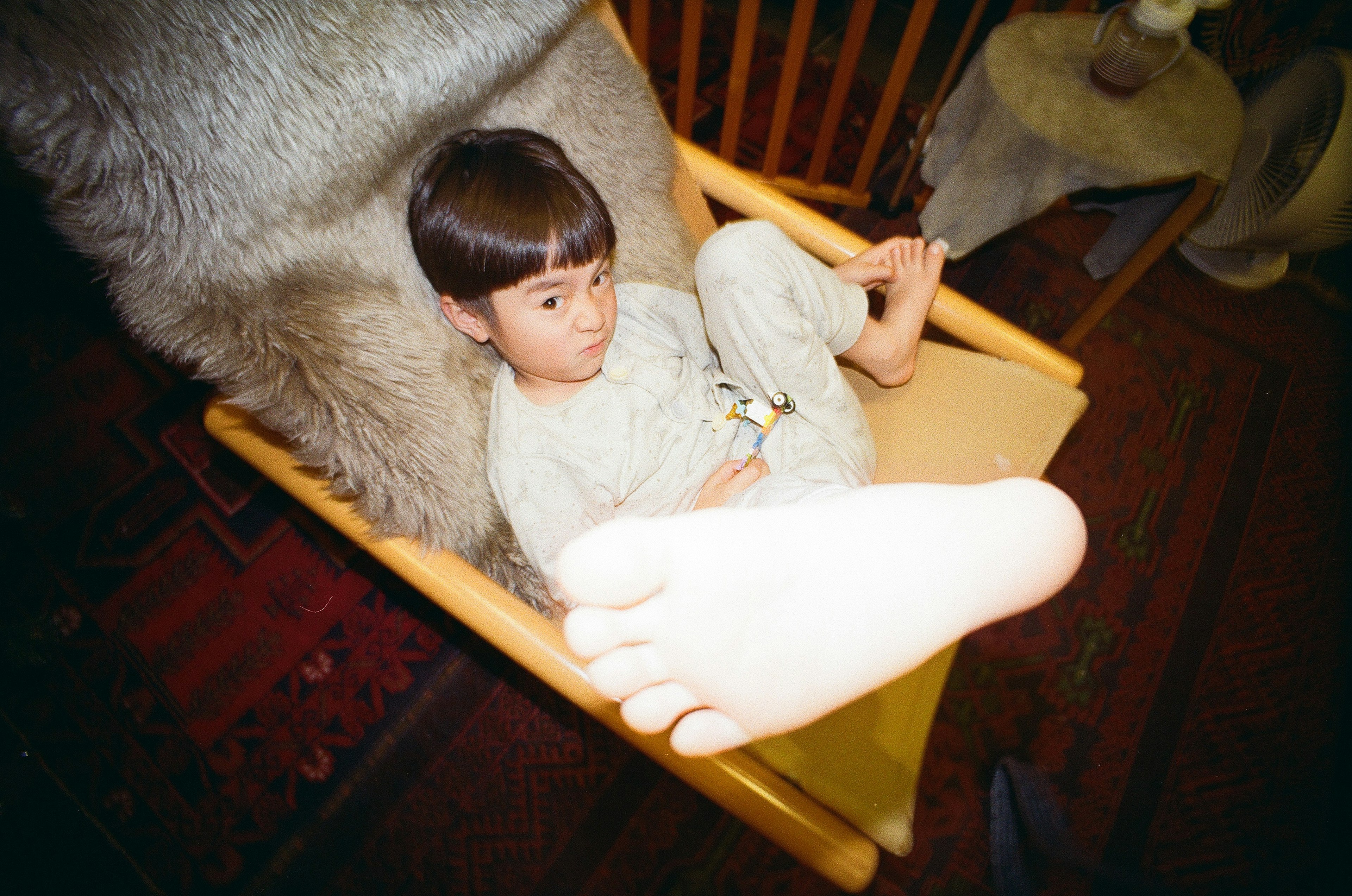 A child sitting in a chair with a large foot in the foreground