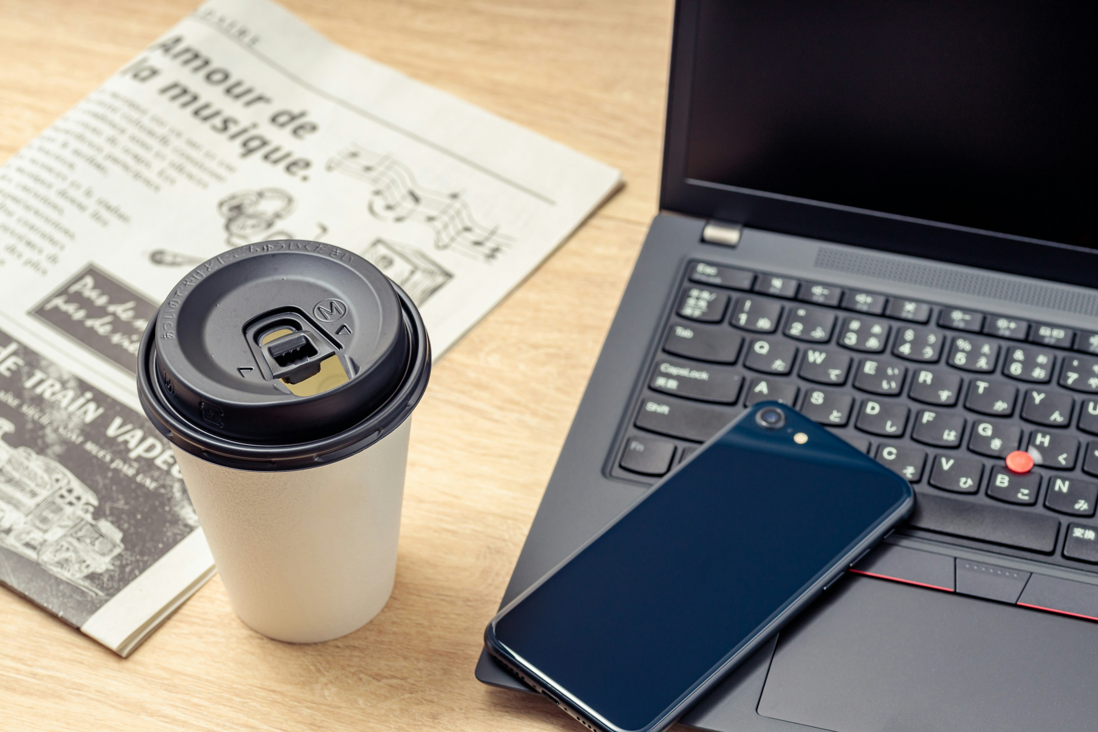 A scene with a coffee cup newspaper and laptop on a desk