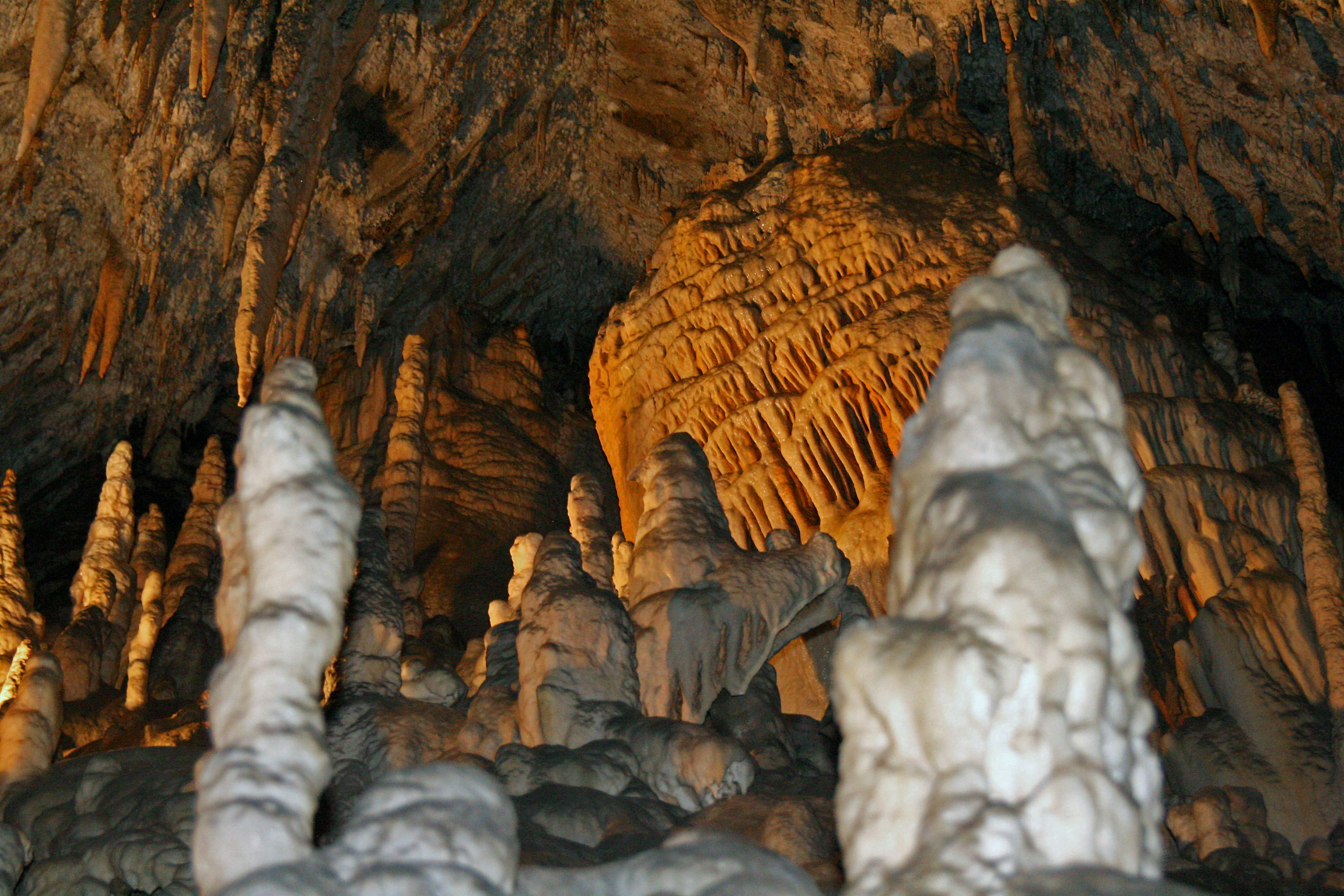 Mysterious cave interior featuring illuminated stalagmites and stalactites