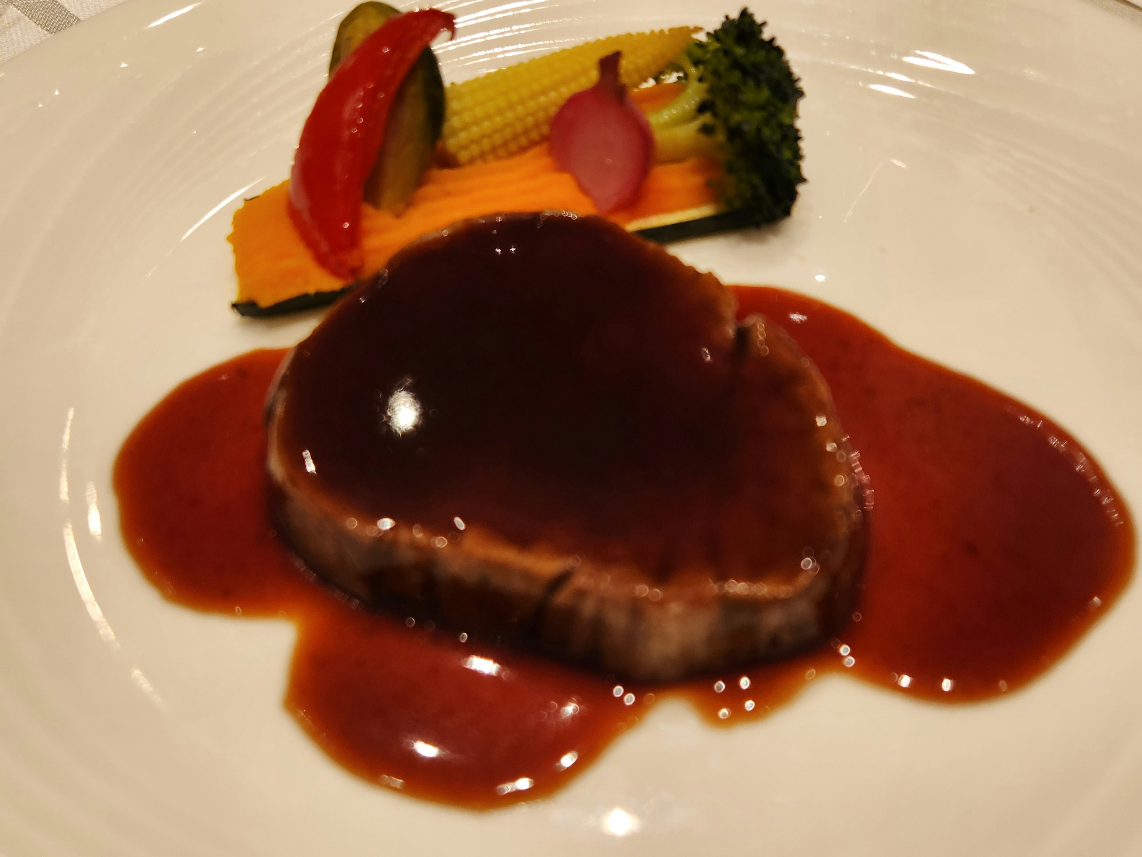 A delicious meat dish with rich sauce accompanied by colorful vegetables on a plate