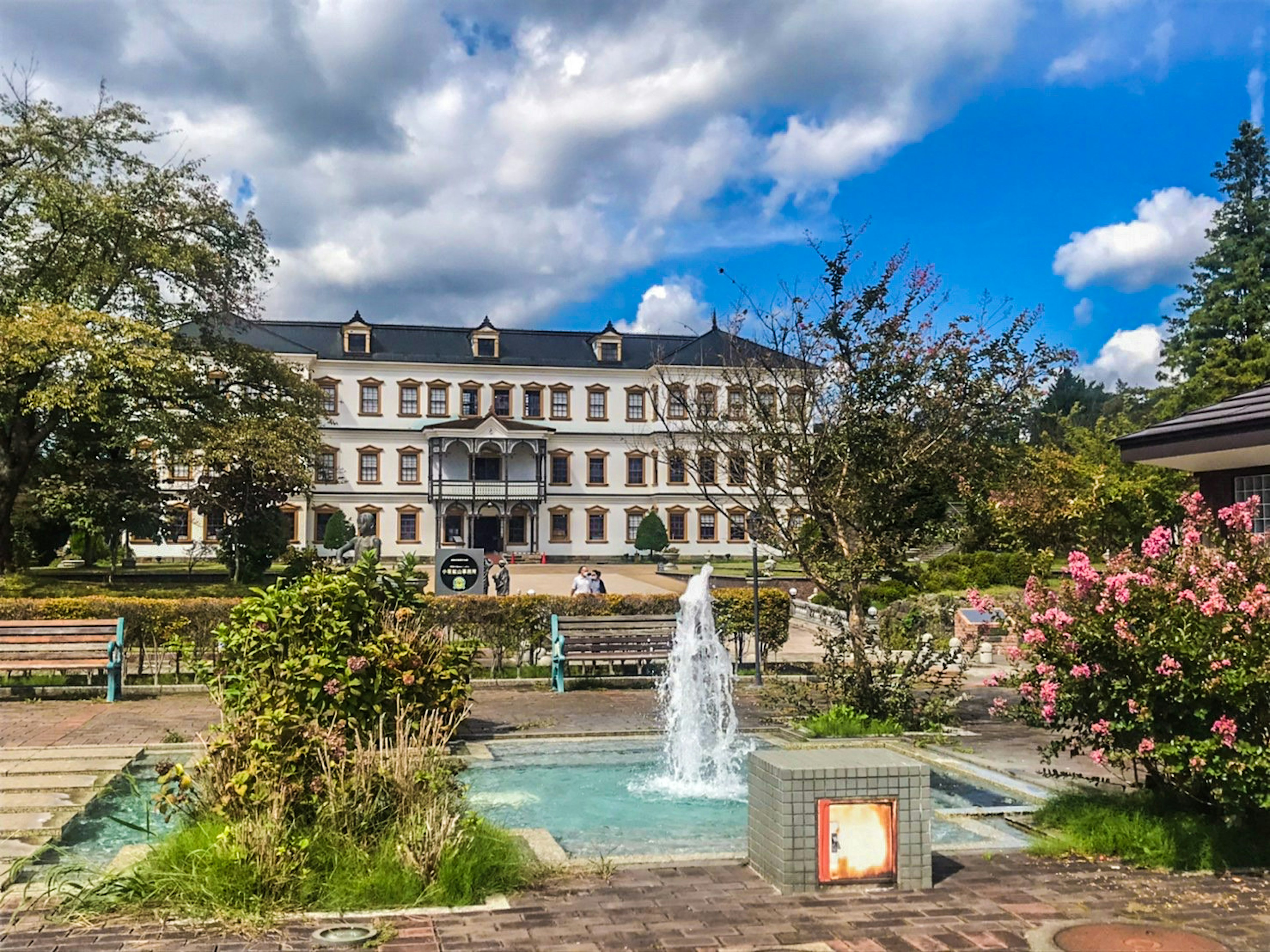 Historic building in a park with a fountain and flowers