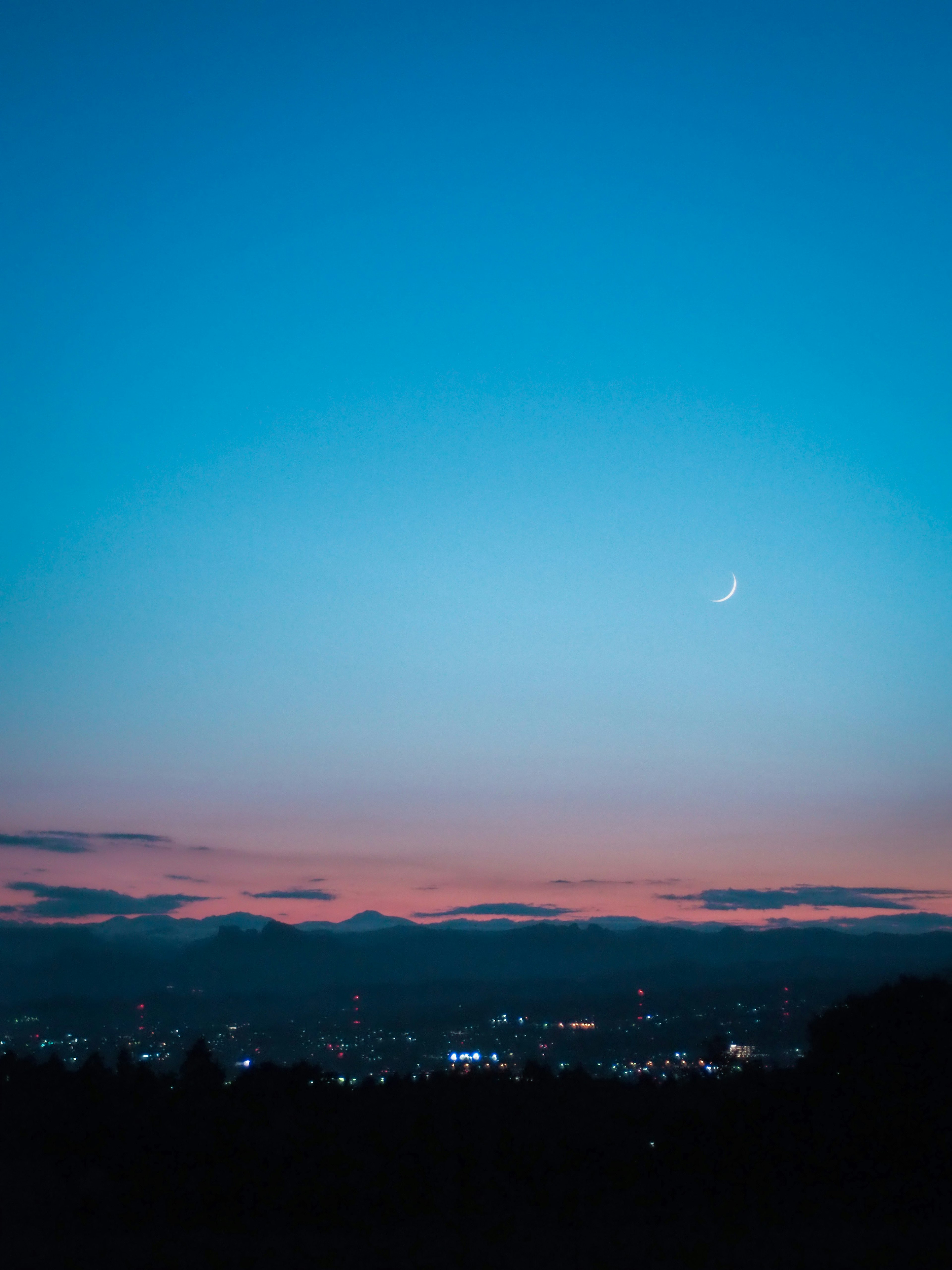 Hermosa escena crepuscular con una luna creciente en un cielo azul