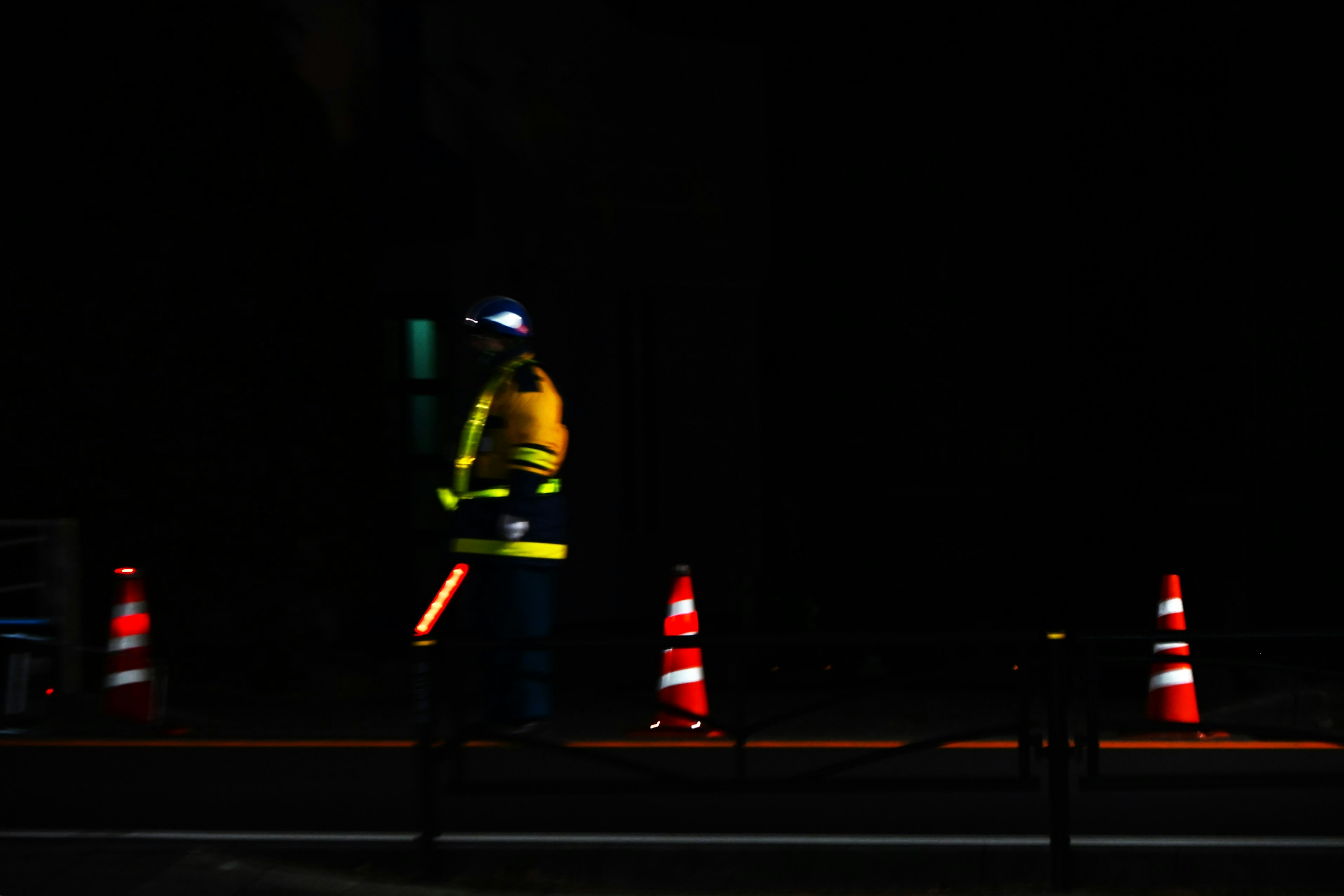 Verkehrskontrollmitarbeiter, der nachts mit orangenen Kegeln arbeitet