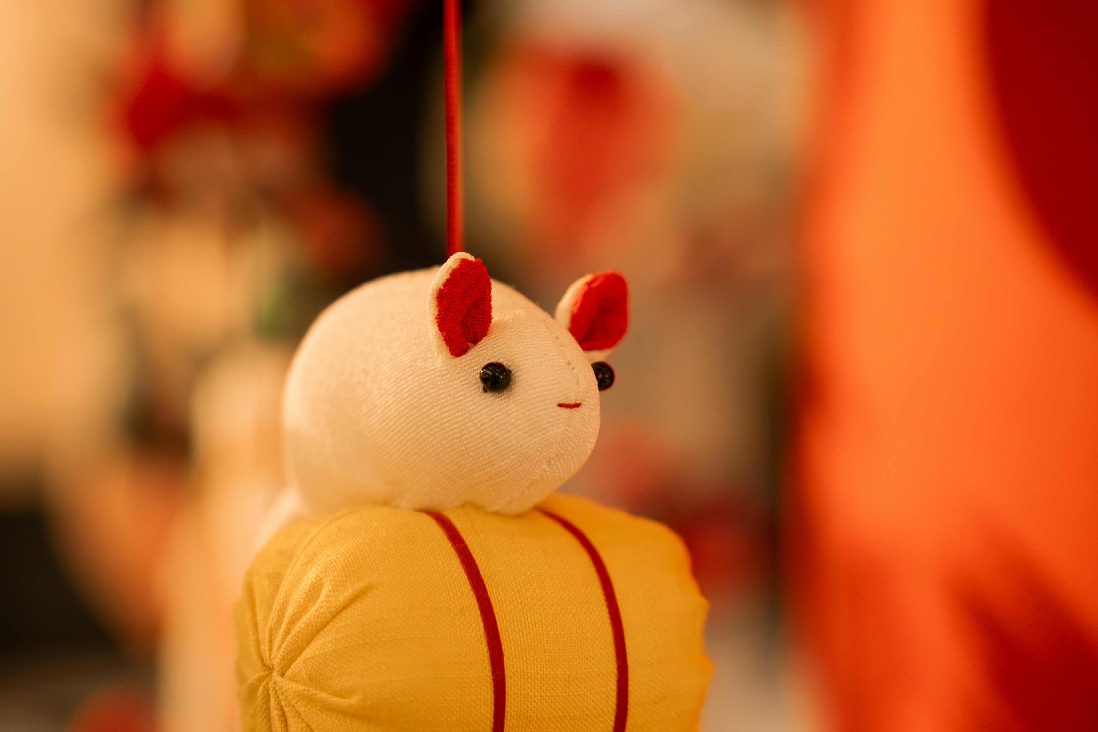 A small white plush animal decoration sitting on a yellow bag