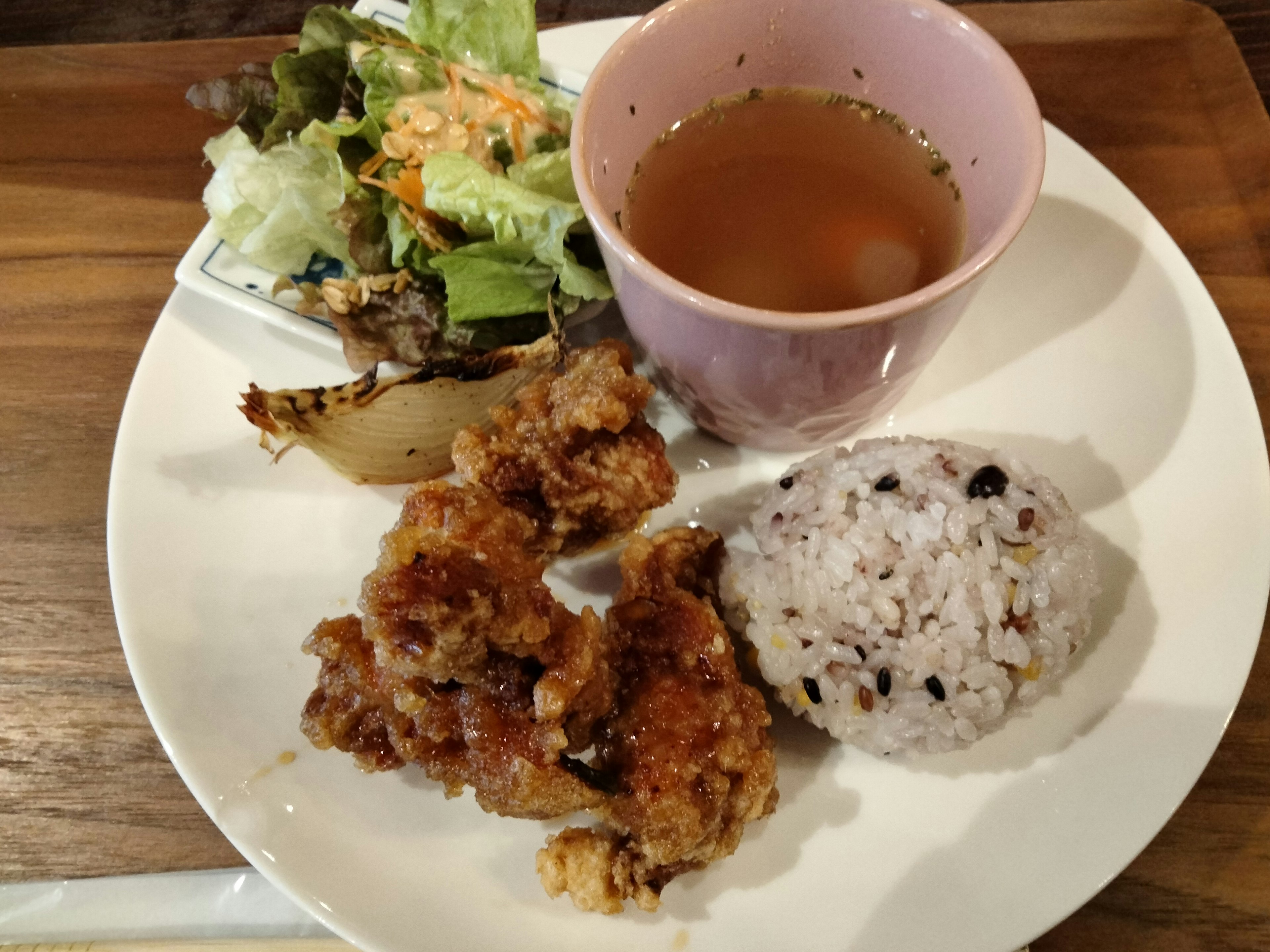 Piring berisi ayam goreng, nasi hitam, salad, dan sup