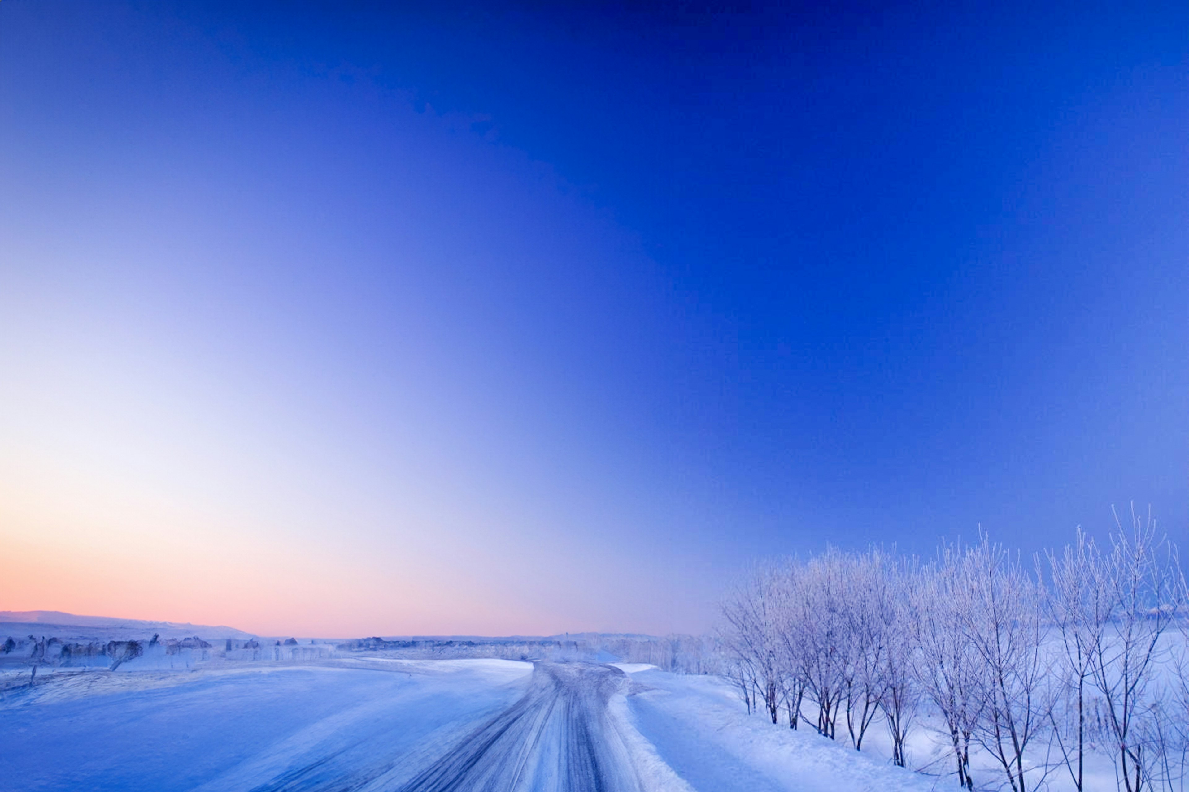 Winter landscape featuring a blue sky and snow-covered road