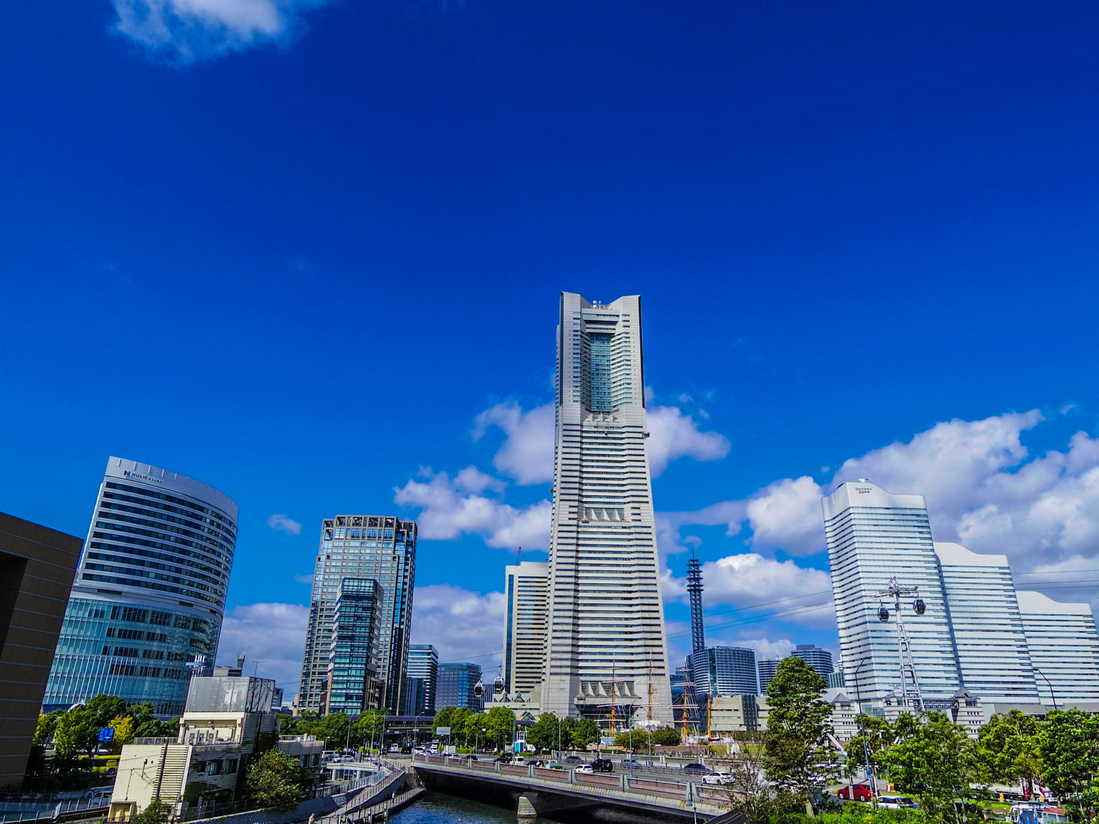 青空の下にそびえる横浜ランドマークタワーと周囲の高層ビル群