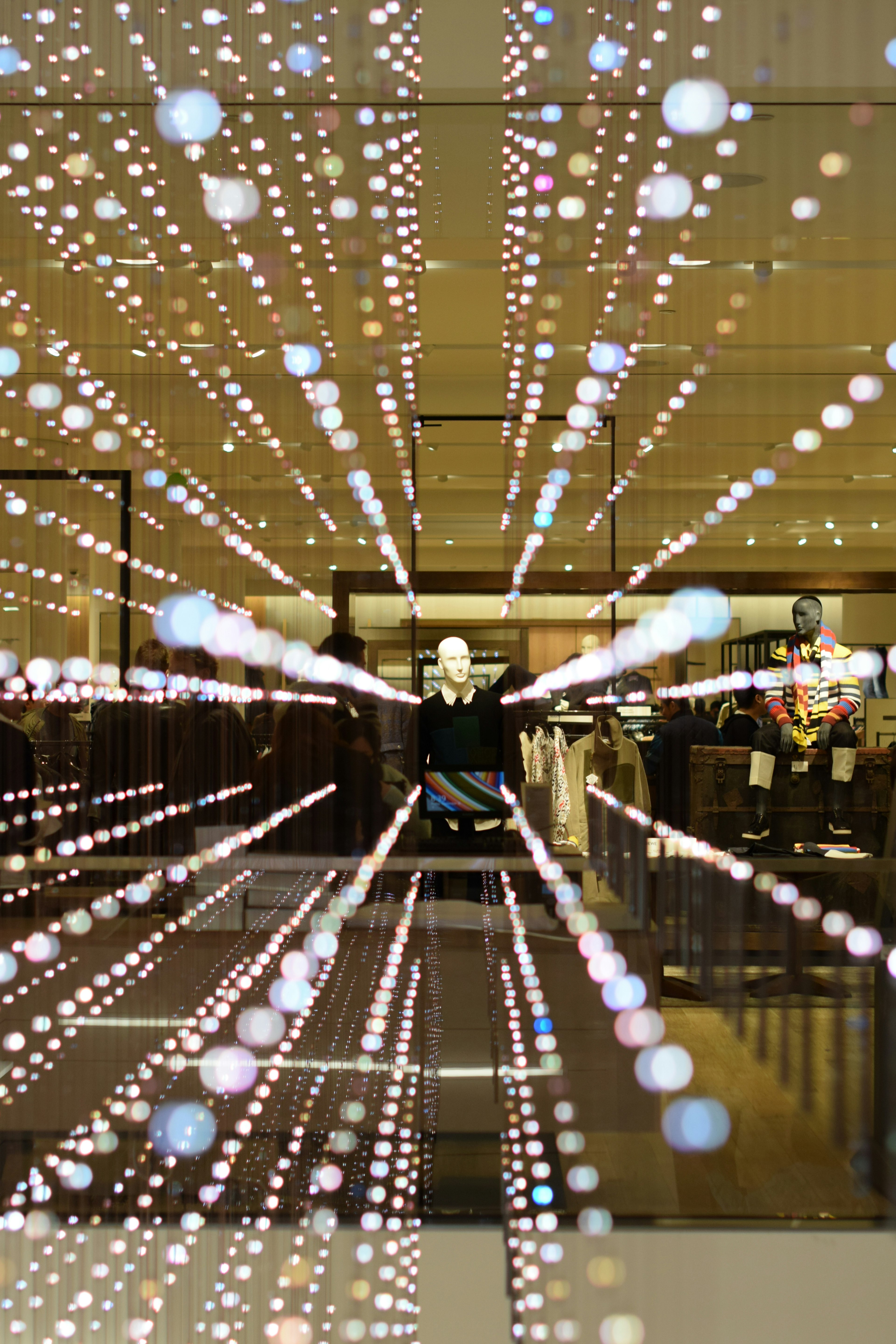 Un maniquí de pie en una vitrina rodeado de puntos de luz