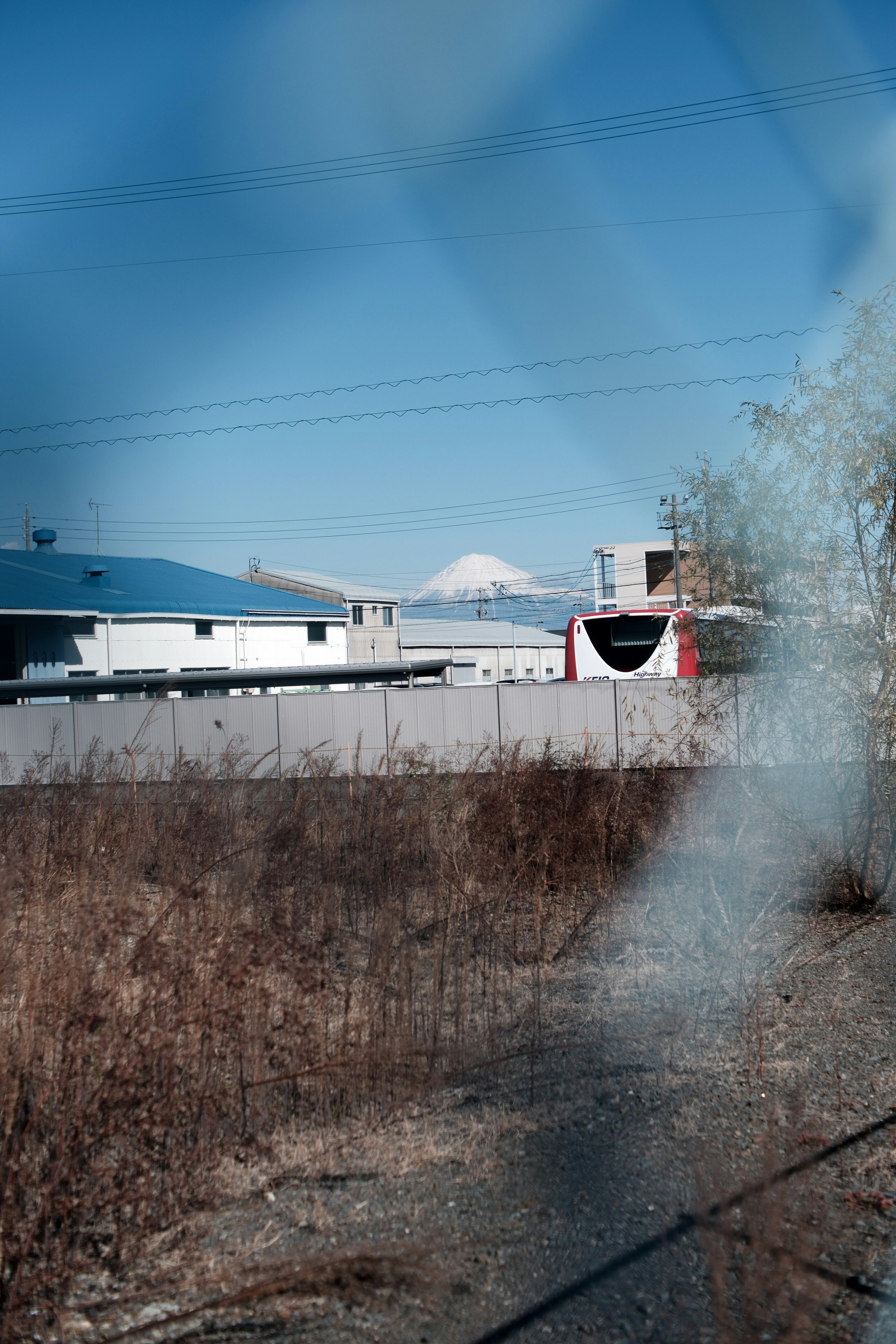Buildings viewed through a fence with a distant mountain