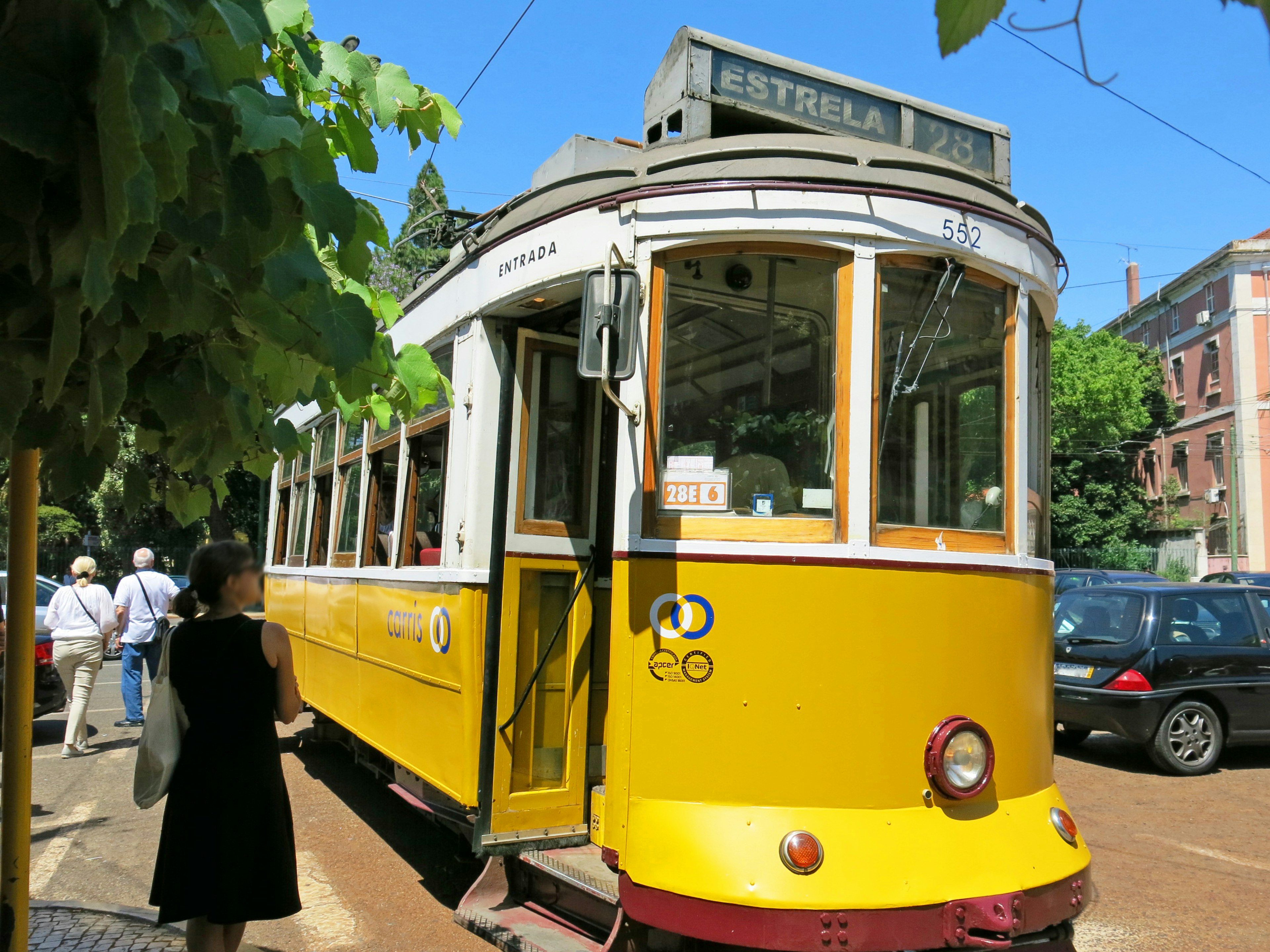 A yellow streetcar with tourists in the background