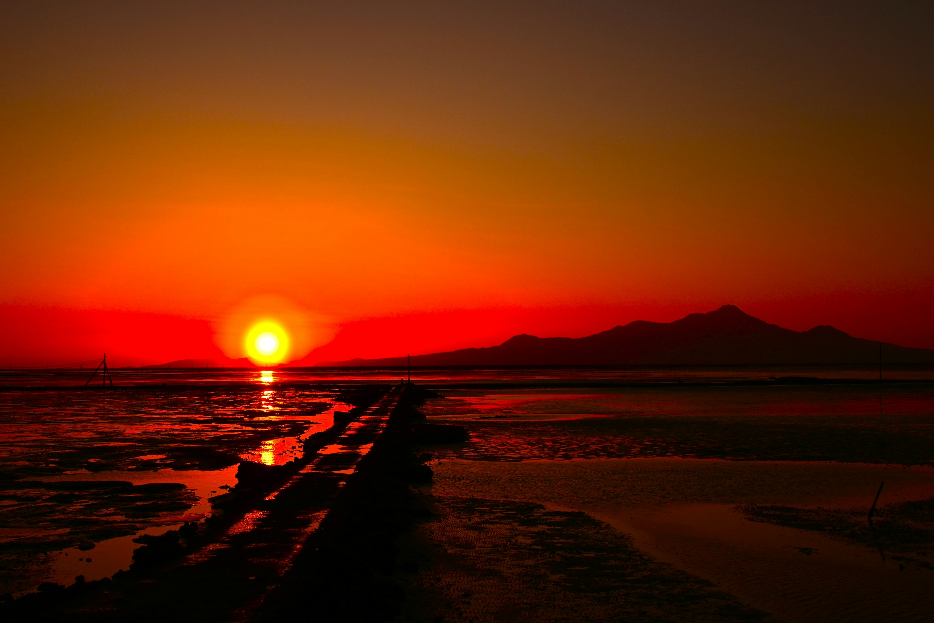 赤い夕日が海に沈み、静かな風景を映し出す