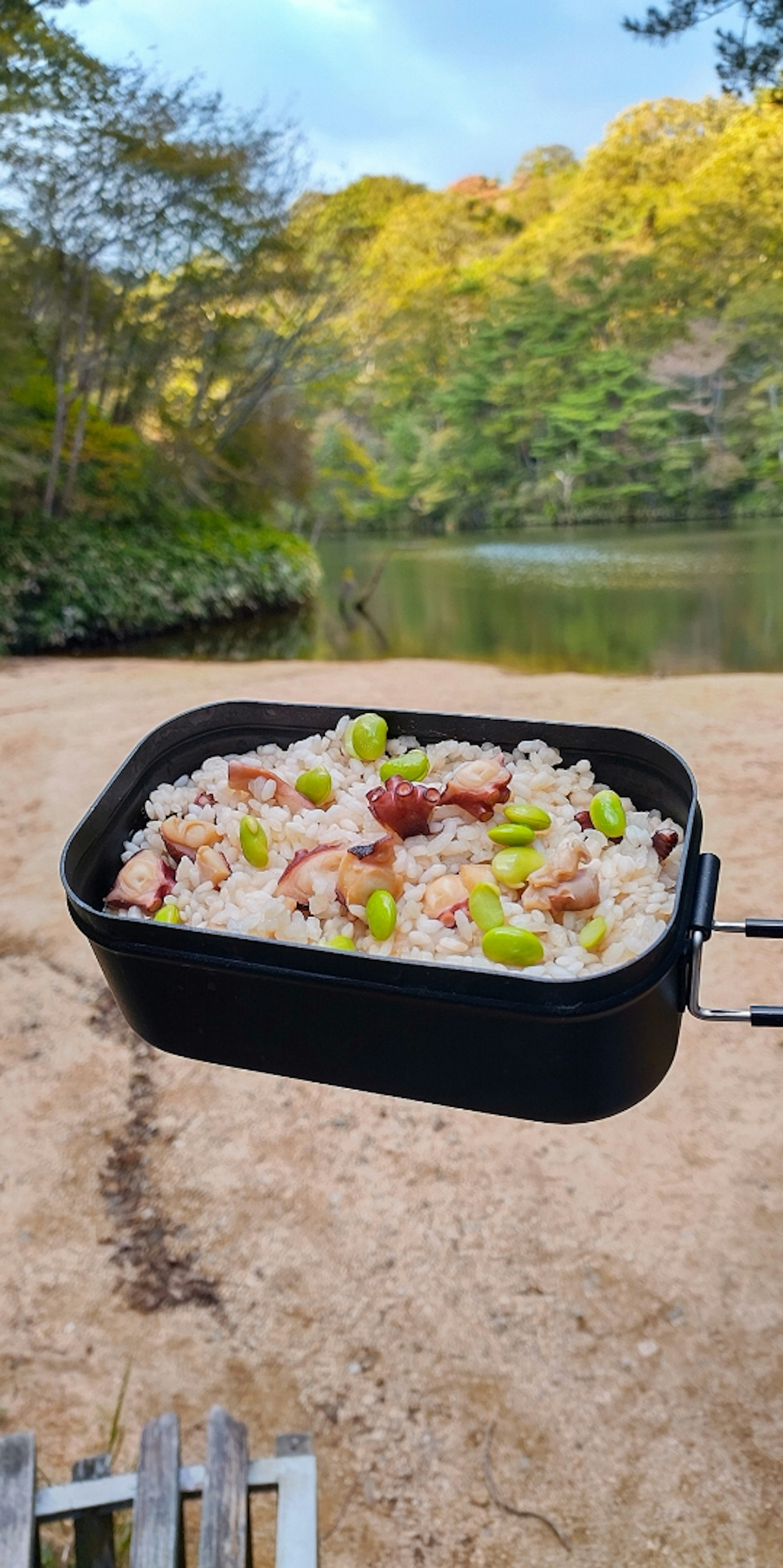 美しい湖の近くで料理されたご飯が黒い鍋に入っている