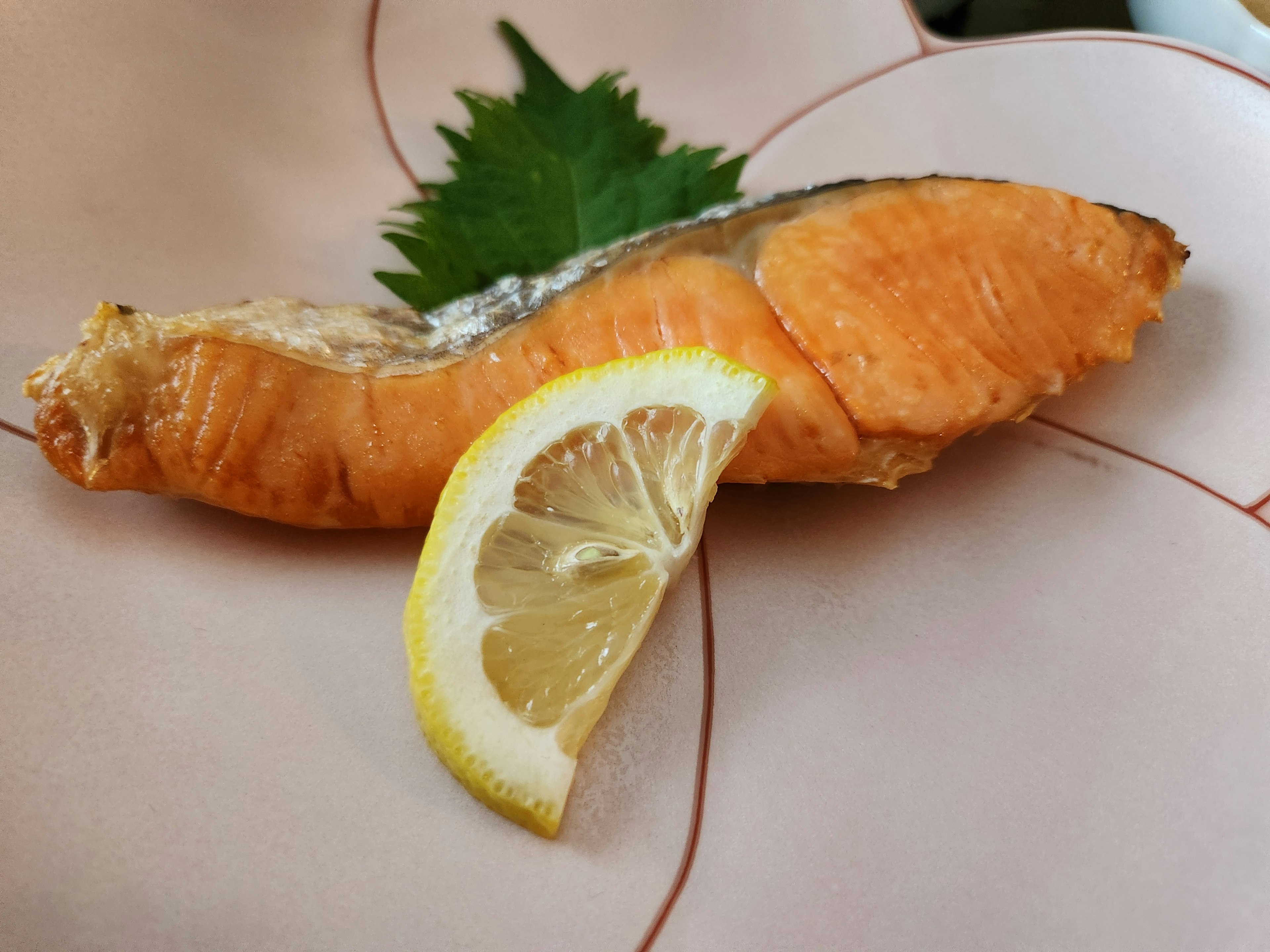 Una rodaja de salmón con una cuña de limón en un plato decorativo