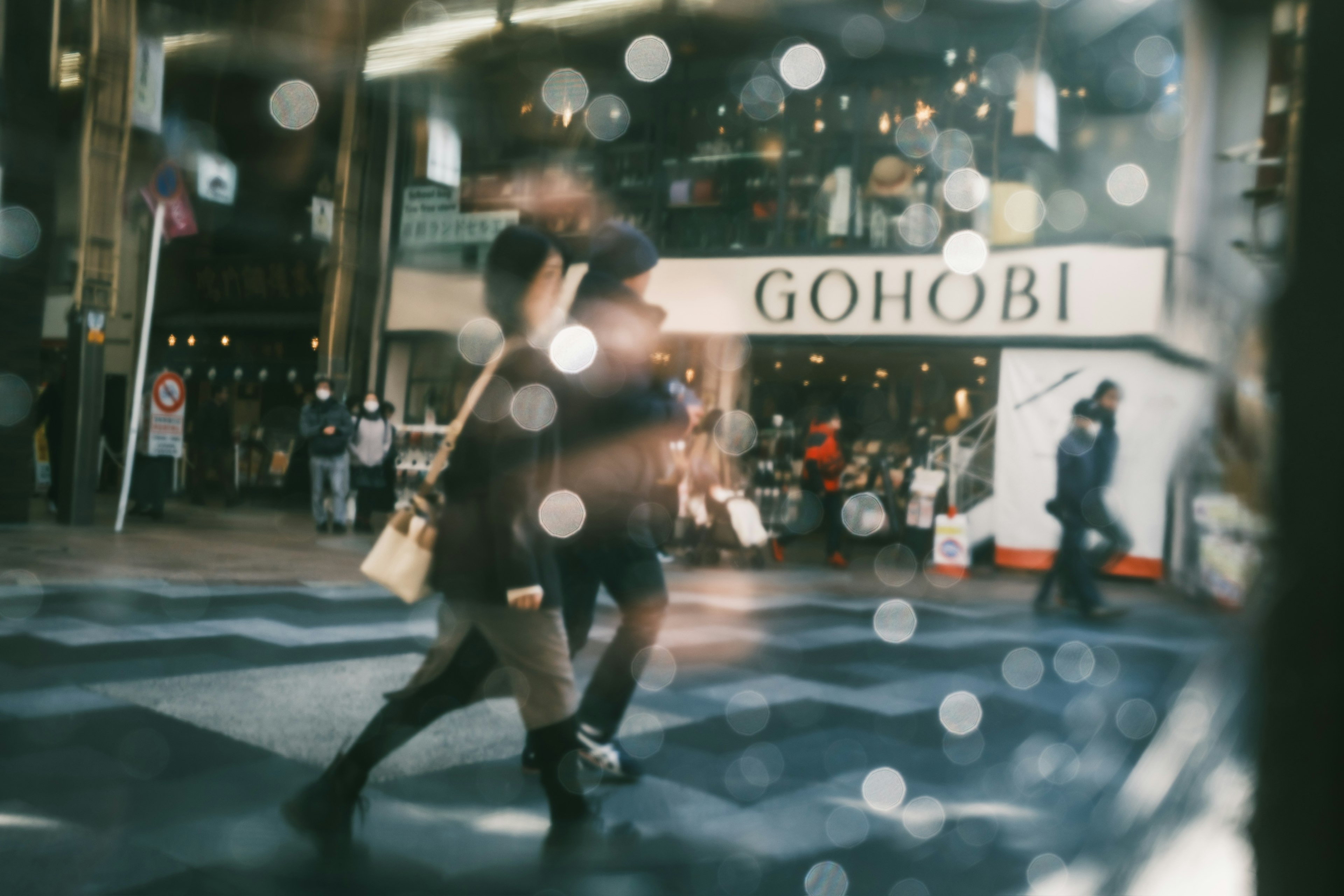 Busy street scene with people walking and Gohobi sign in background