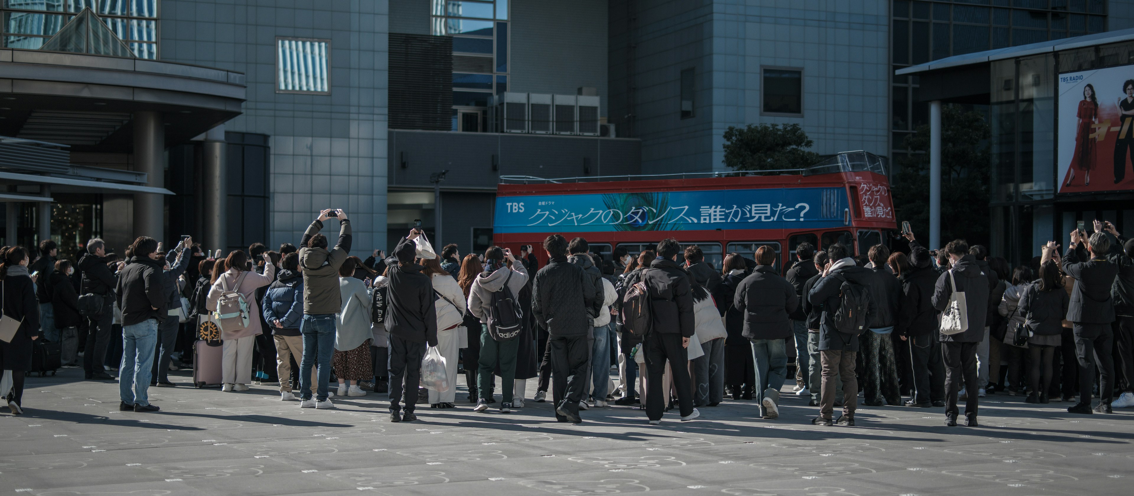 Crowd of people gathered in an urban setting with a bus in the background