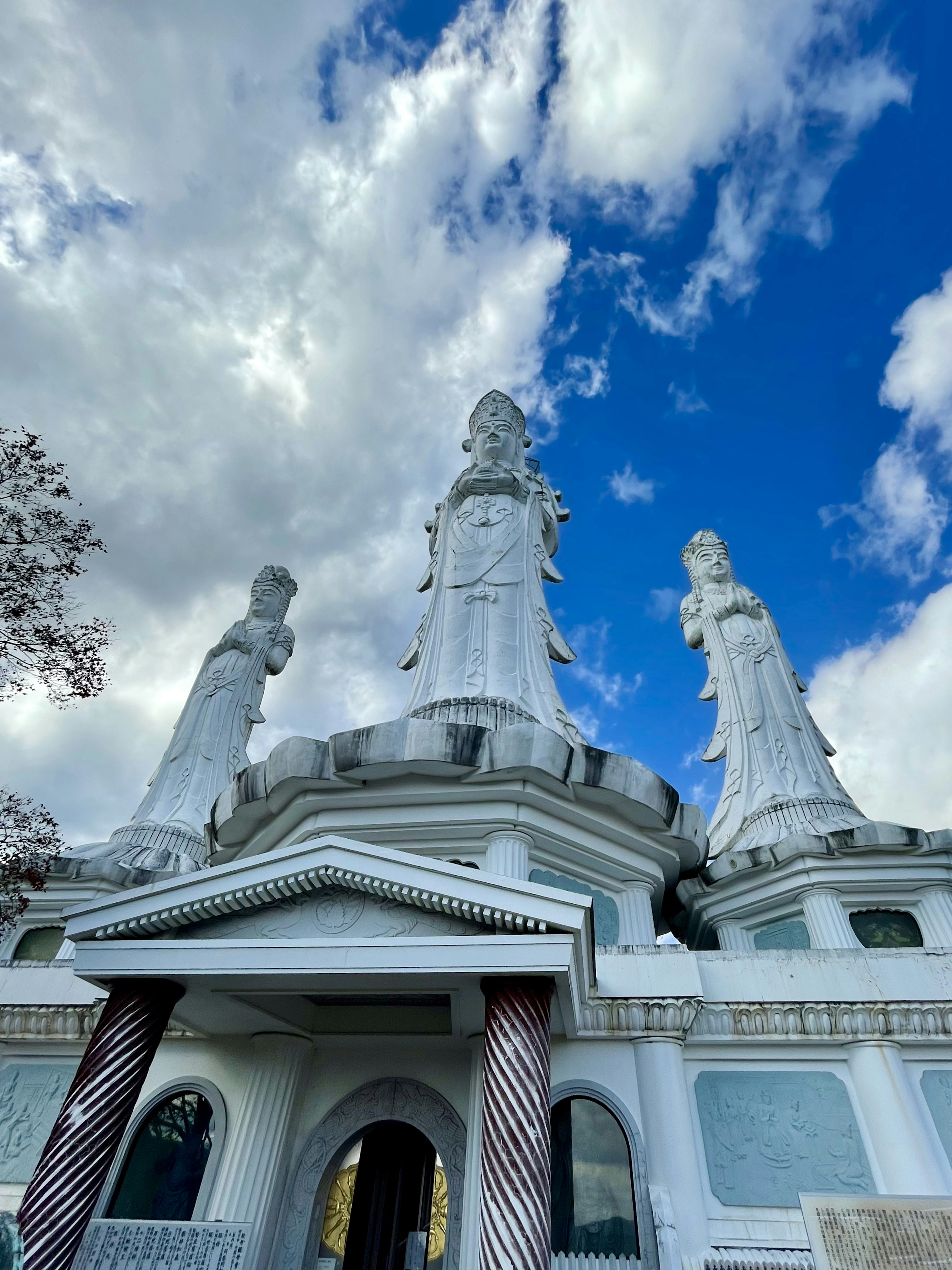 Außenansicht eines Tempels mit weißen Statuen und blauem Himmel