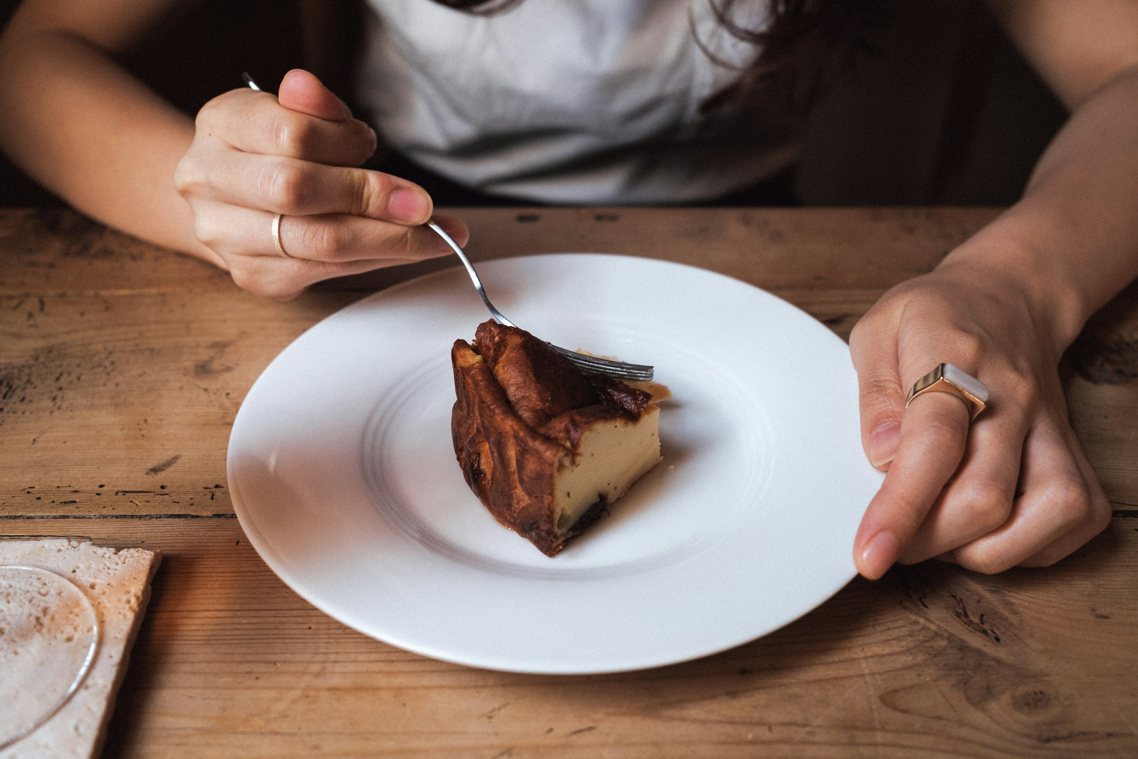 A woman holding a fork about to eat a slice of cake on a white plate