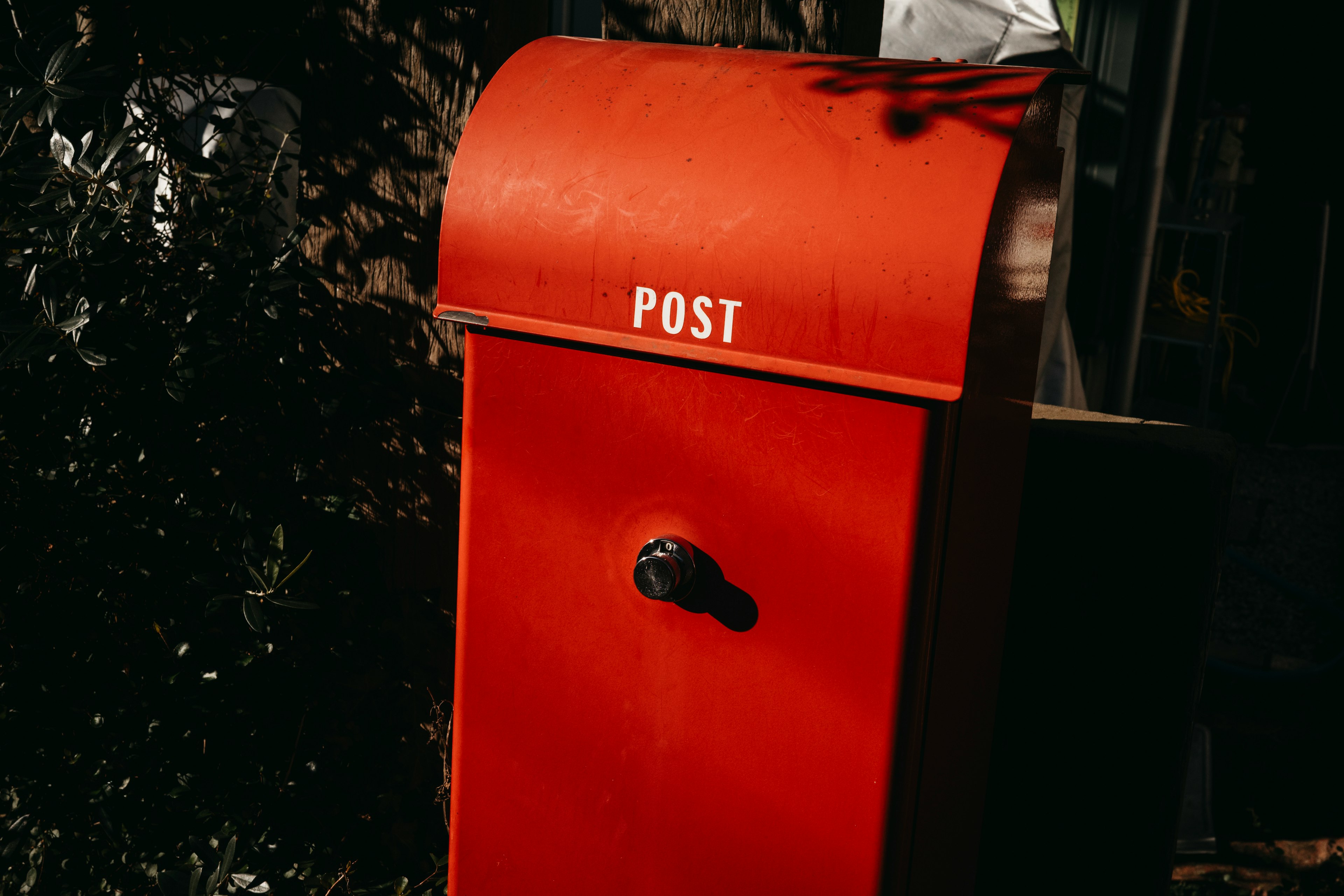 Cassetta postale rossa con la scritta POST visibile in un giardino