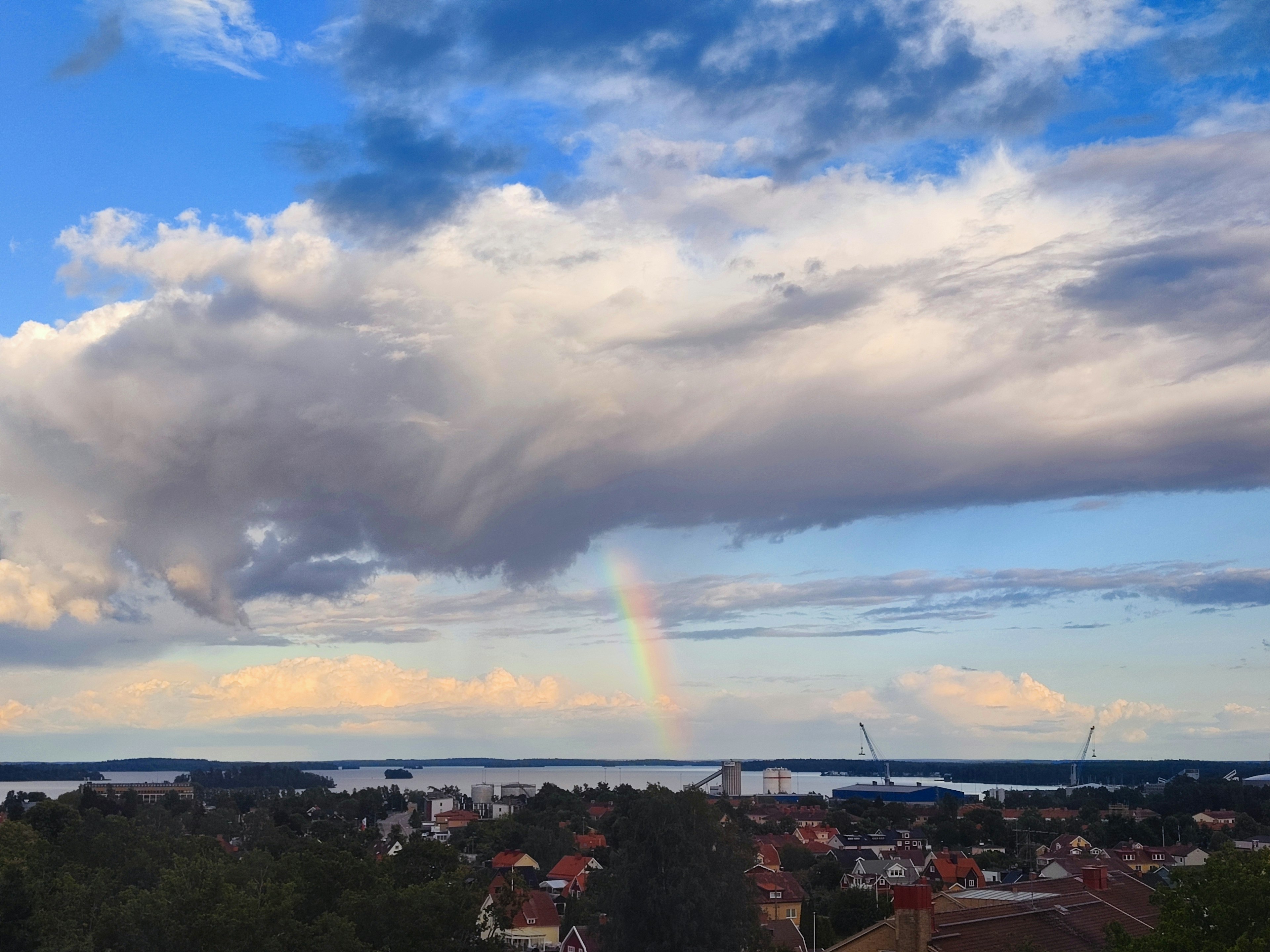 Une vue pittoresque d'un arc-en-ciel sur un ciel bleu et des nuages au-dessus d'une ville