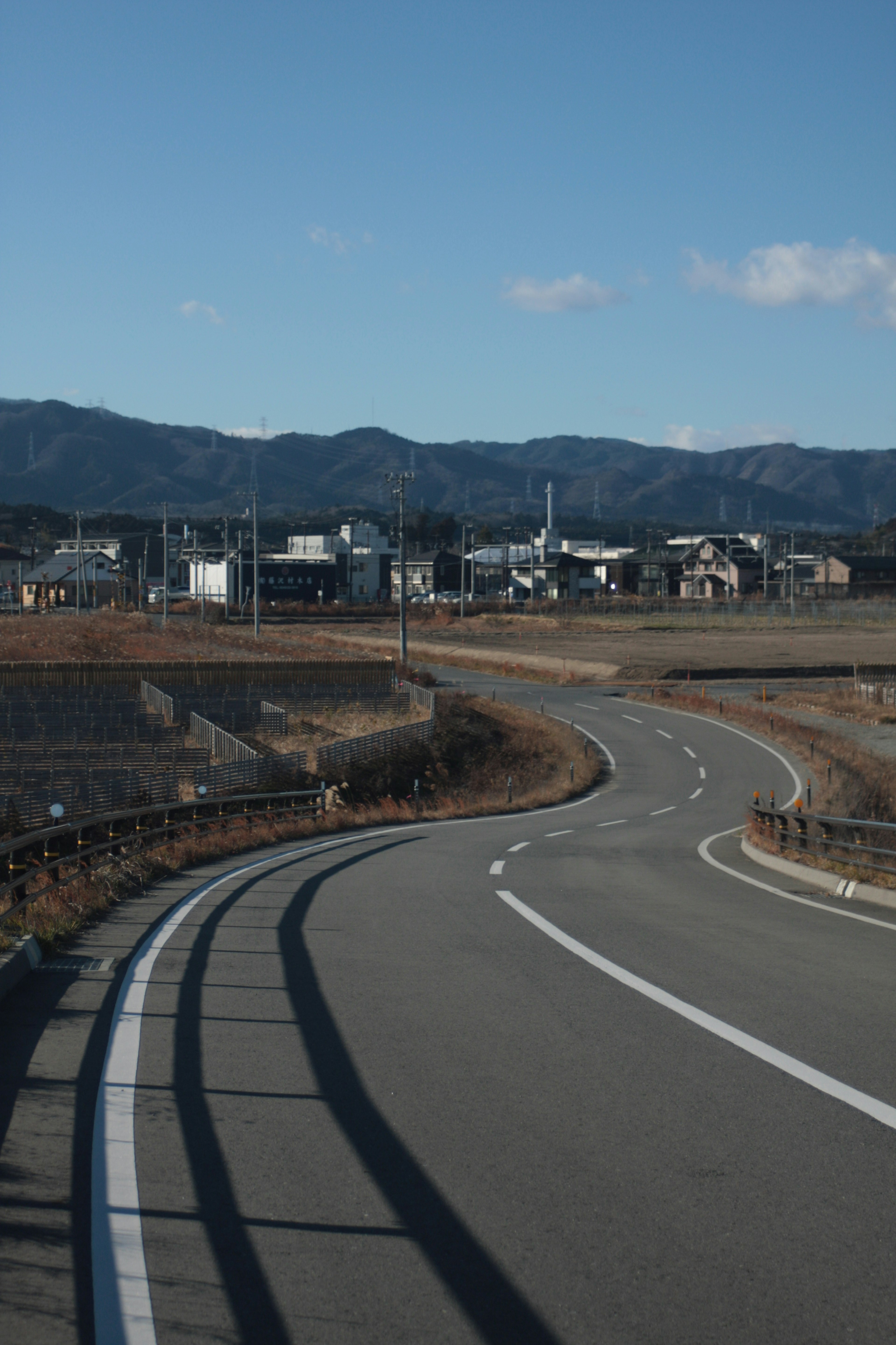 Carretera curva con fondo montañoso y edificios rurales